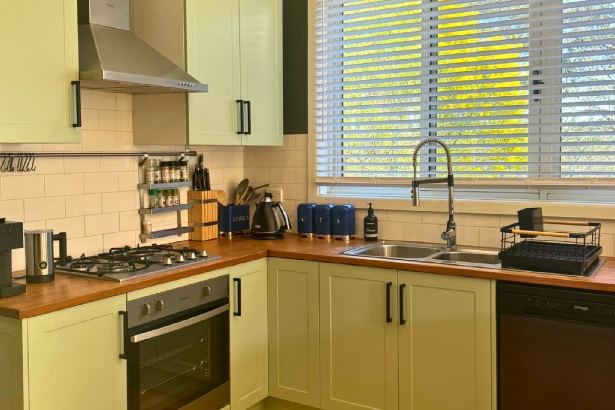Modern kitchen at Katoomba holiday cottage with gas cooktop, oven, dishwasher and timber benchtops.