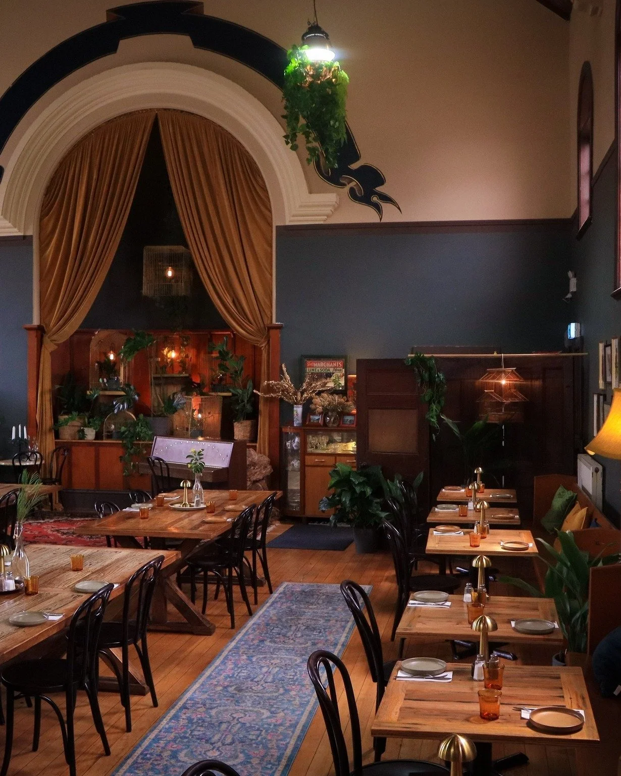 Stylish restaurant interior with warm lighting, wooden tables and indoor plants at Bowery