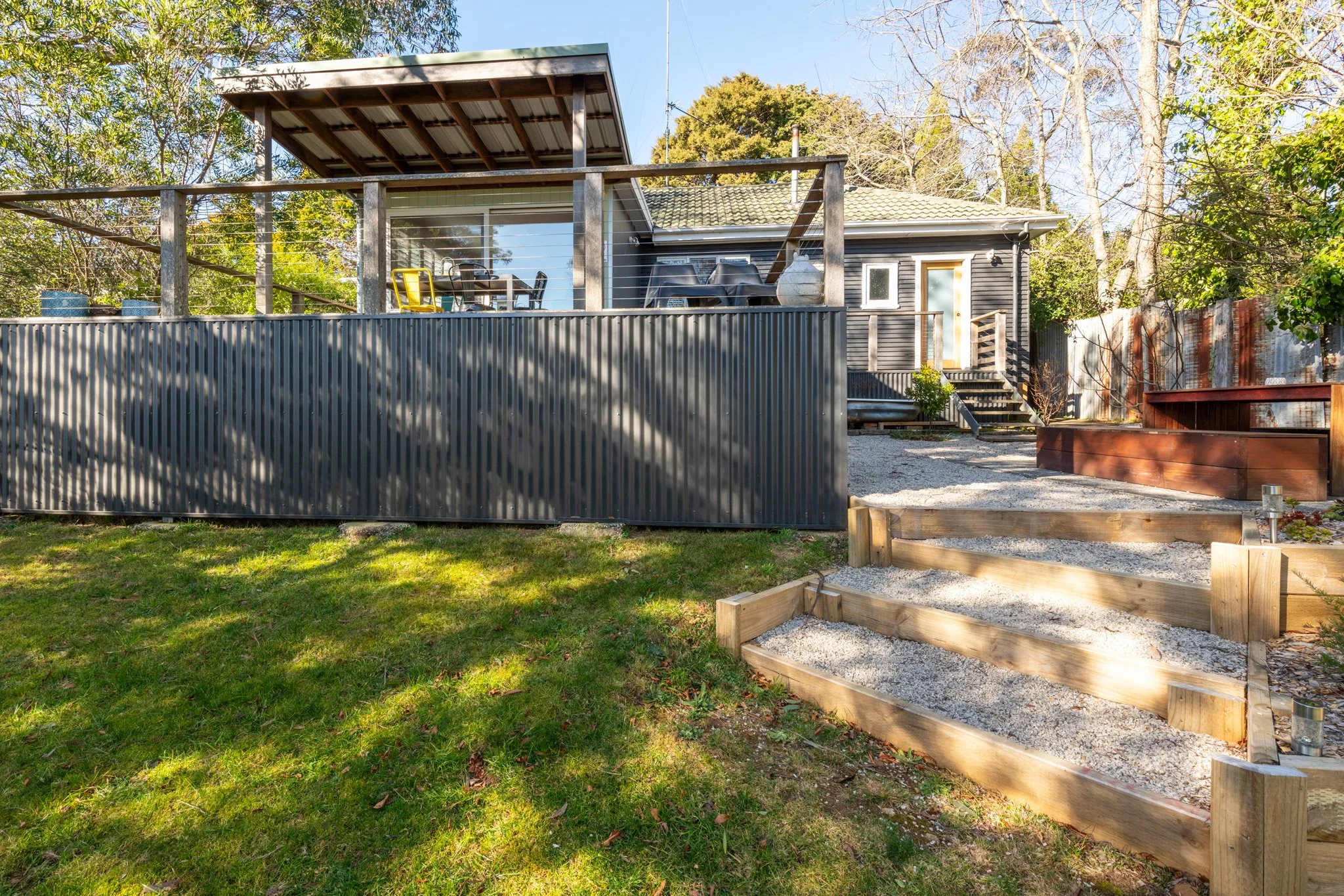 “Exterior of Katoomba holiday cottage with elevated deck, outdoor dining area and landscaped garden in the Blue Mountains.