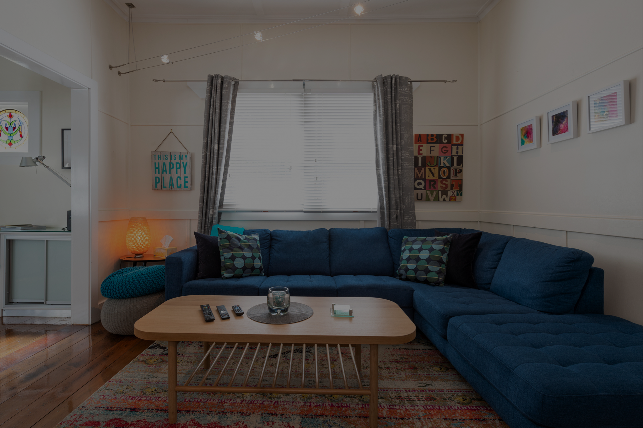 Living area in Blackheath, Blue Mountains featuring a blue L-shaped sofa, timber coffee table and colourful décor.