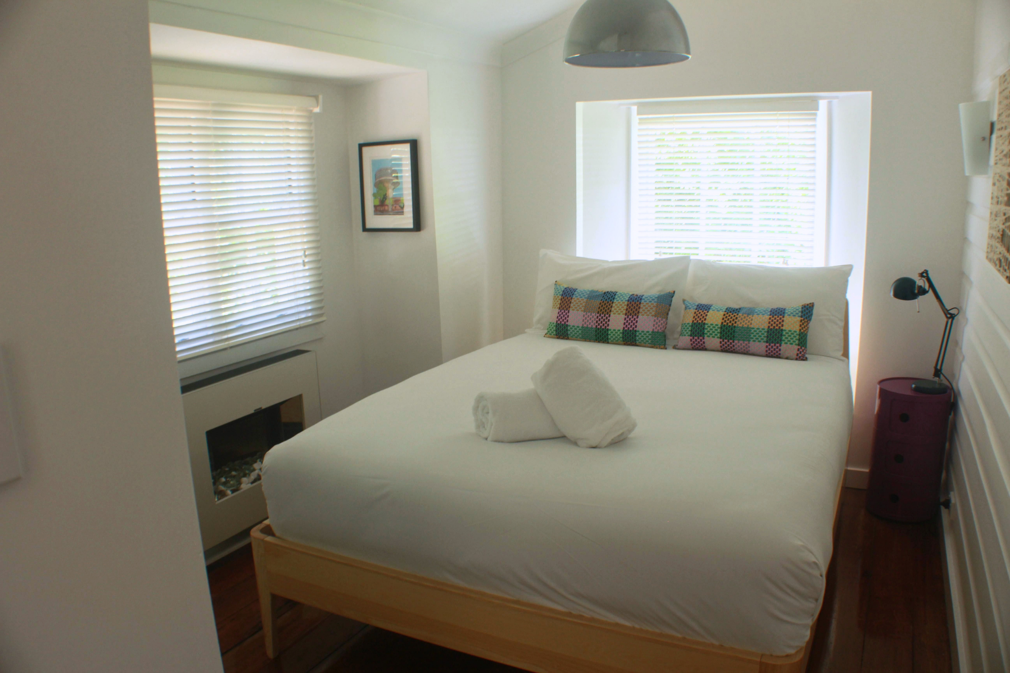 Bright and cosy bedroom in Blue Mountains holiday home with comfortable bed, natural light and fireplace for added warmth.