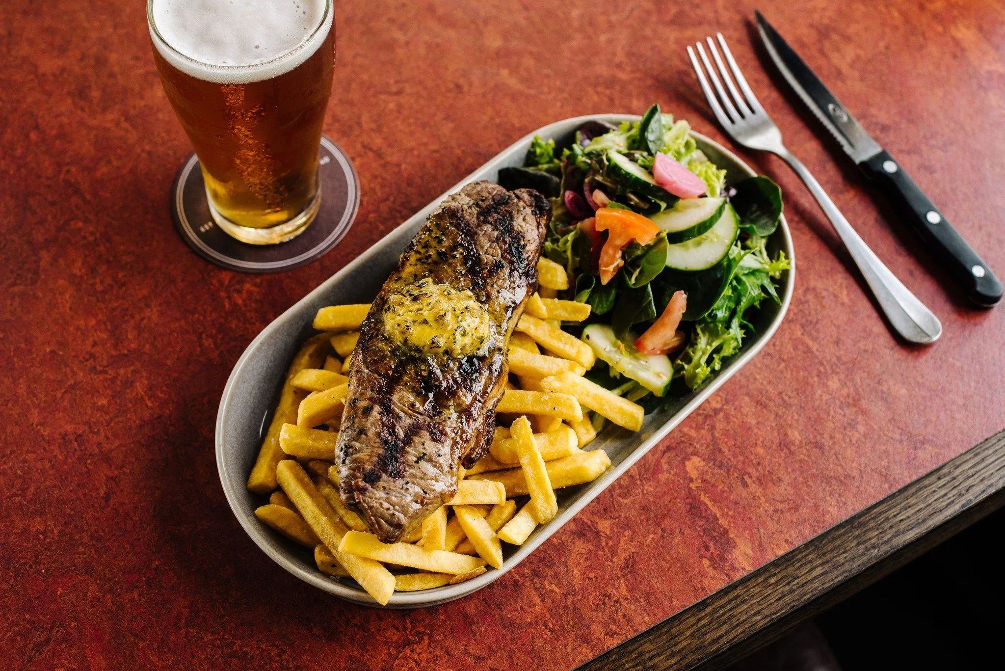 Steak with chips and salad served with a glass of beer at New Ivanhoe Hotel Blackheath