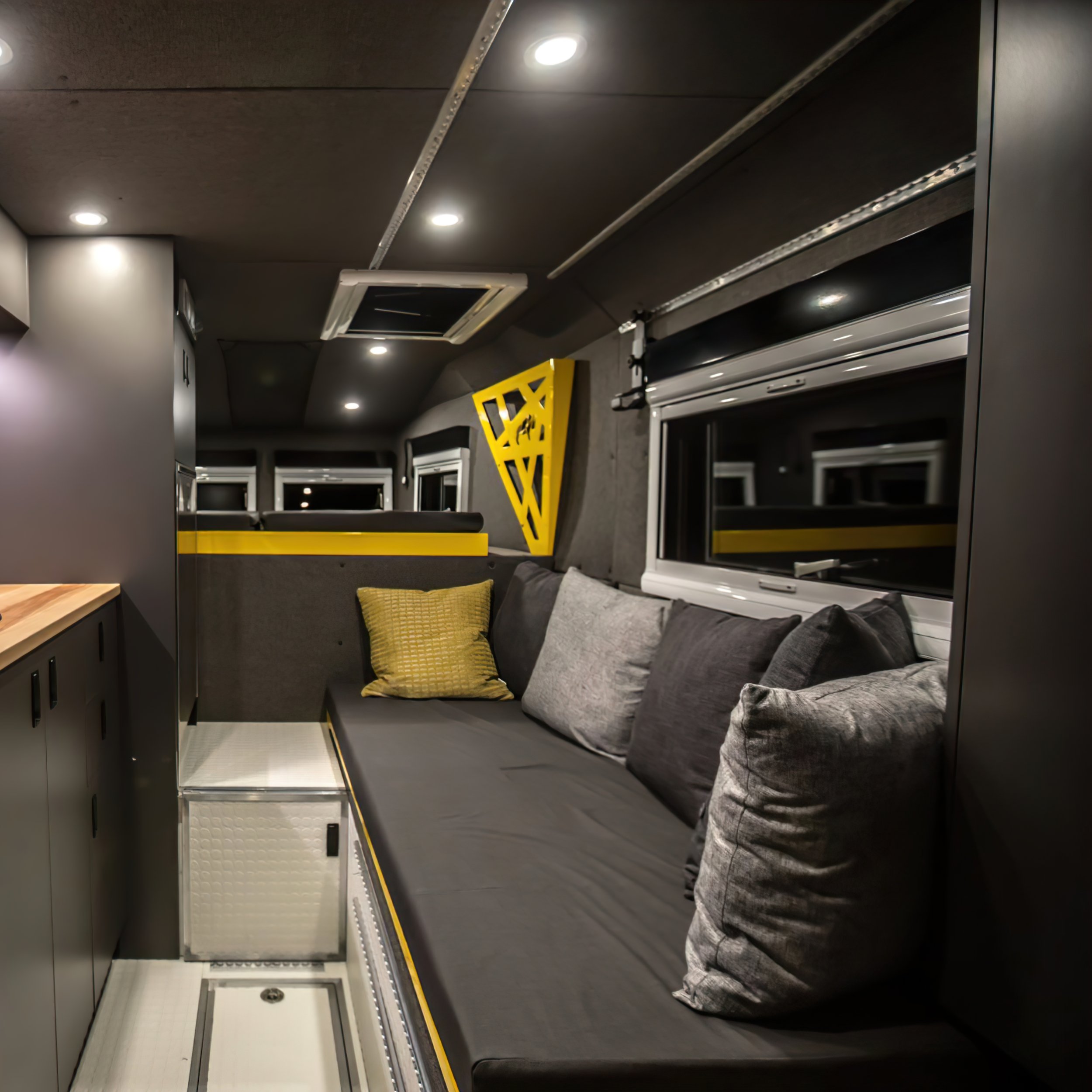  Beside that is the kitchenette, with a portable induction cooktop, fridge, and countertop space. Space isn’t an issue, with three storage cabinets and storage pockets.  The over-cabin sleeping area is large enough for a queen-sized bed with USBs a-p