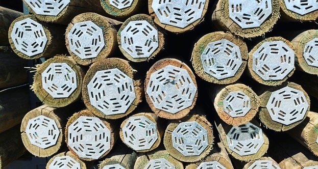 Stacked timber poles with nail plates on the ends to protect them