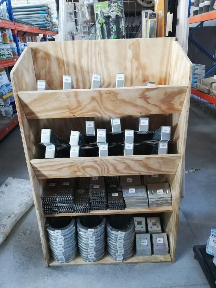 Wooden display shelf with metal brackets and fasteners in a hardware store.