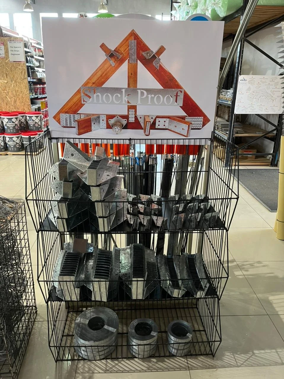 Metal connectors and fasteners display at a hardware store labeled 'Shock Proof'