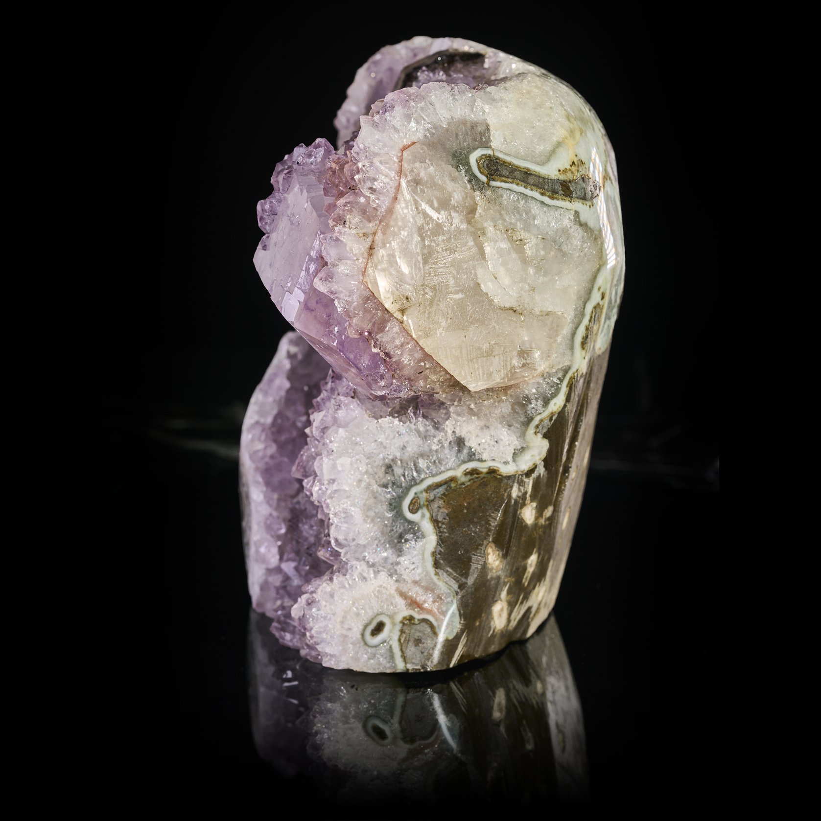 Image Description: A side angle shot of a amethyst freeform with calcite and tourmaline.