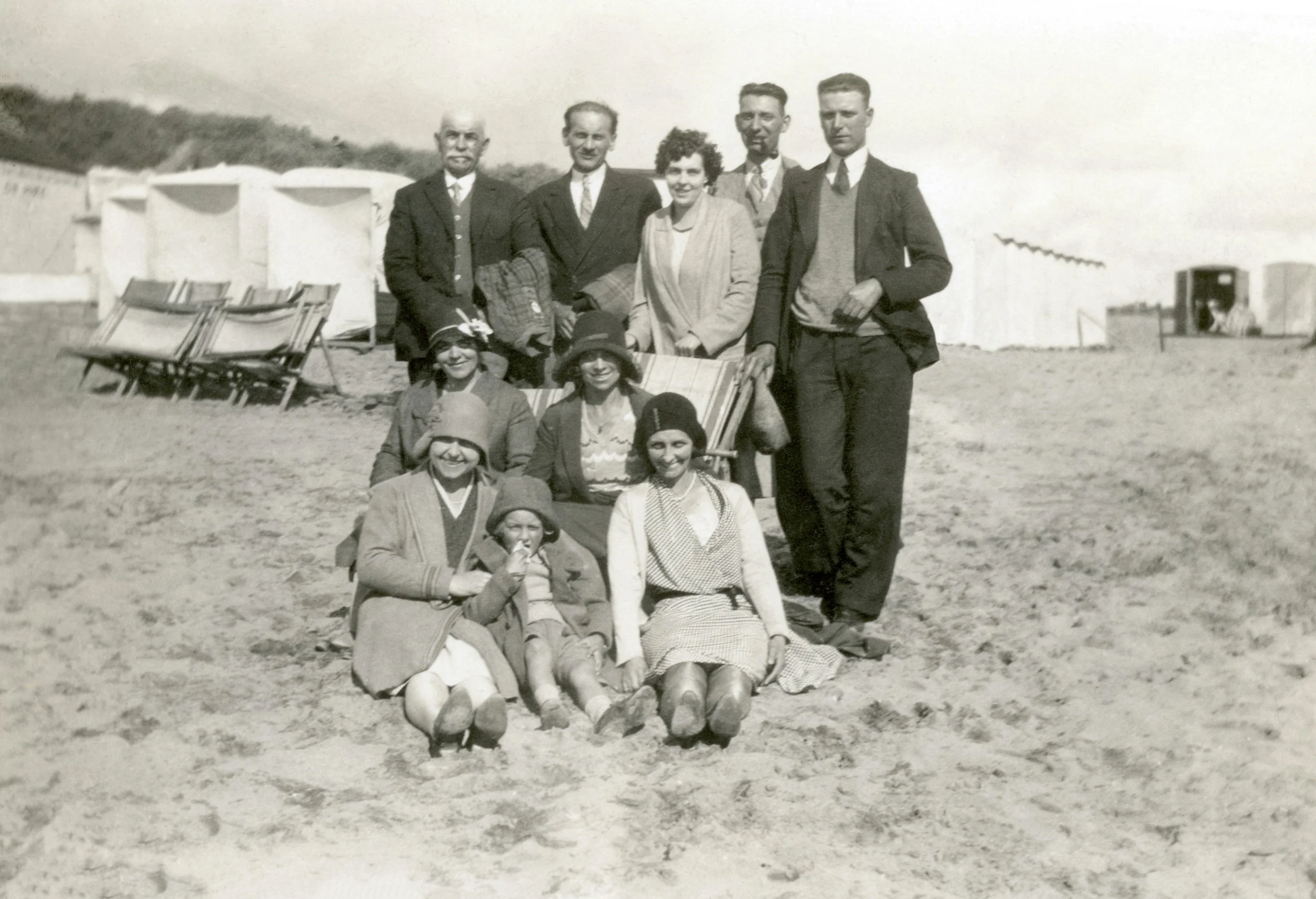Old photo of community members on a beach. Men and women.
