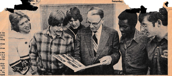 Members of the Cornell university's lightweight football team looking at photos from the 1976 Silk Bowl tour