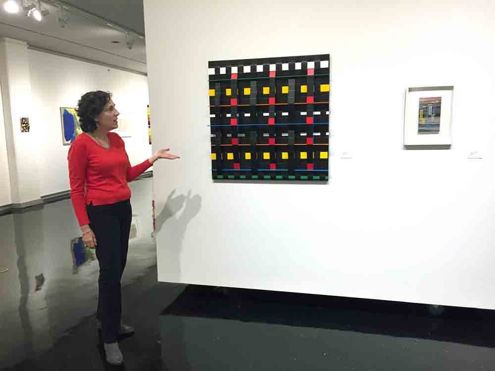 AAA Vice President Emily Berger discussing the show in front of a work by Susan Bonfils. A work by Irene Rice Pereira is to the right.