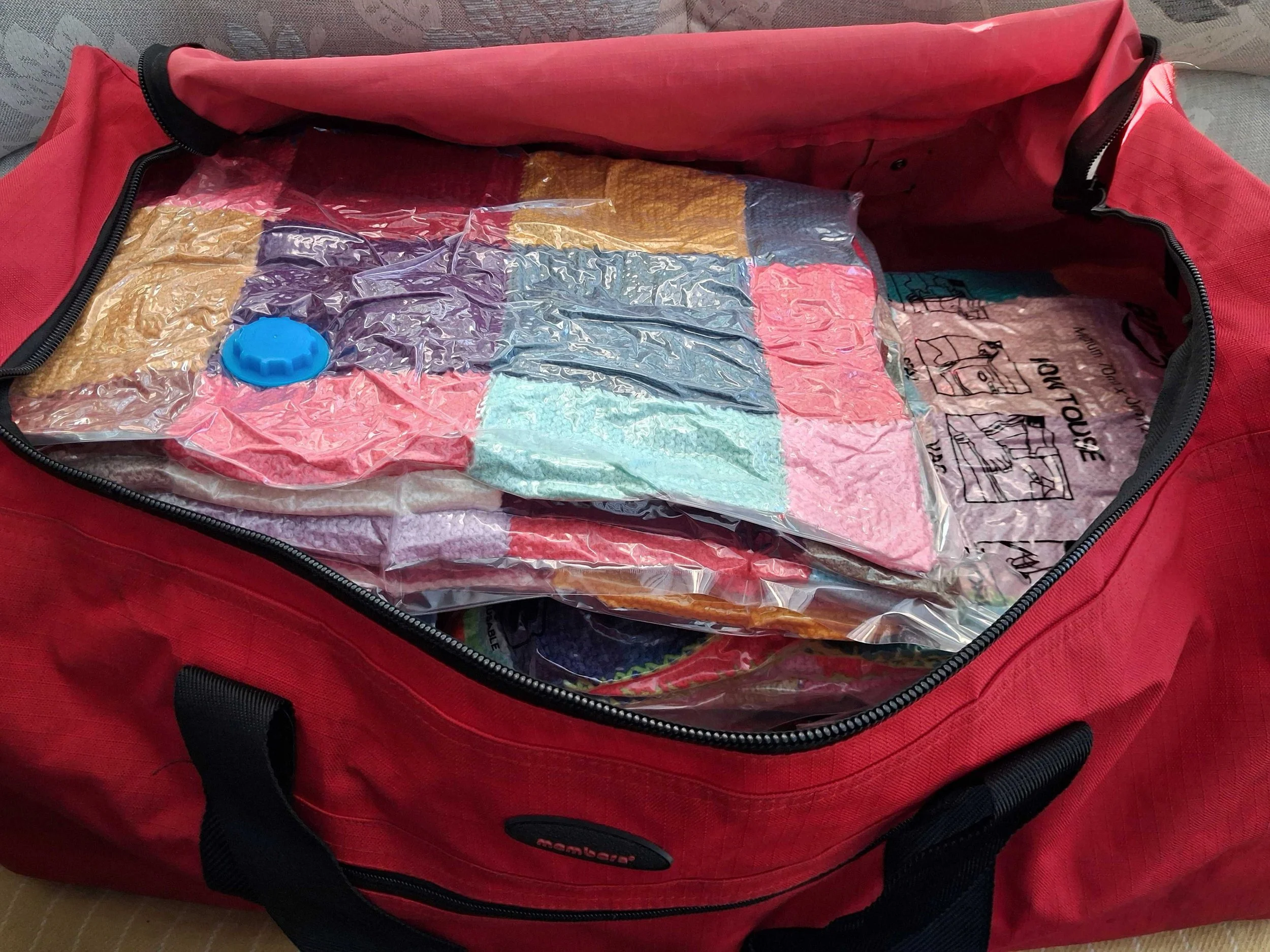 Colourful knitted blankets, vacuum packed into a holdall bag.