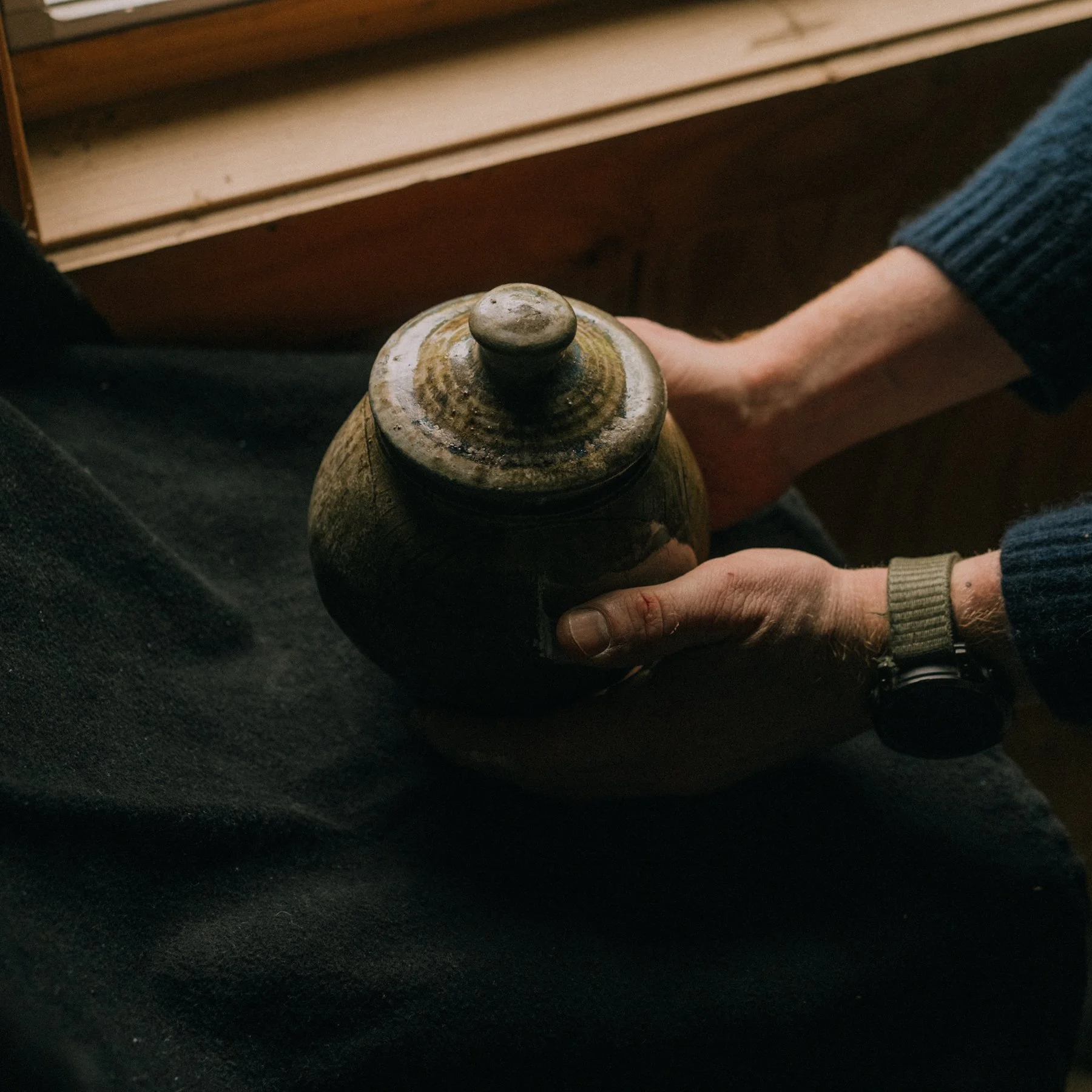 Hands holding a stoneware jar