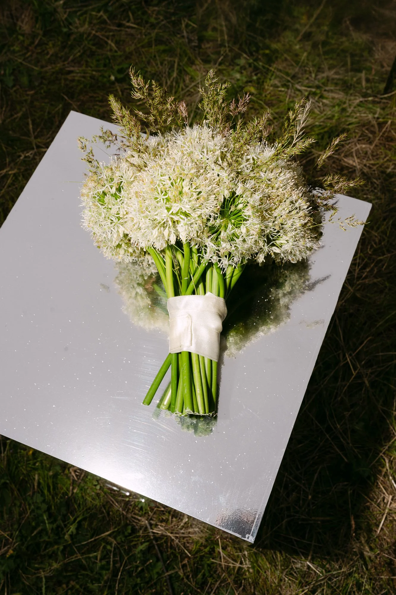 White wedding bouquet resting on mirror in Cappadocia landscape — editorial bridal detail photography