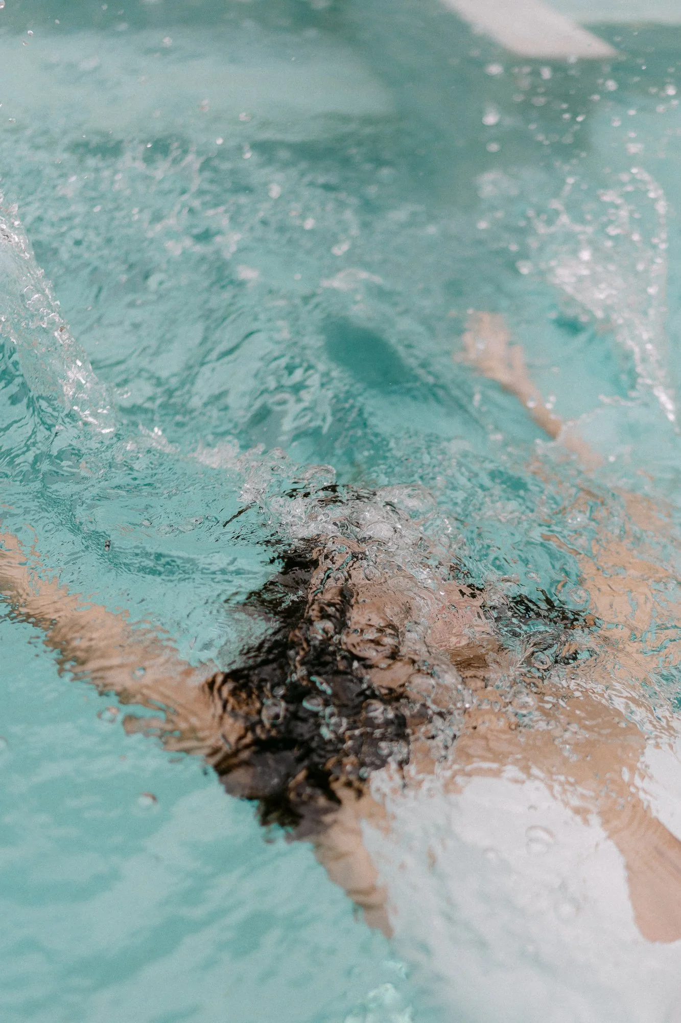 Aerial view of woman diving into turquoise pool, hair fanning out — abstract editorial photography Tuscany