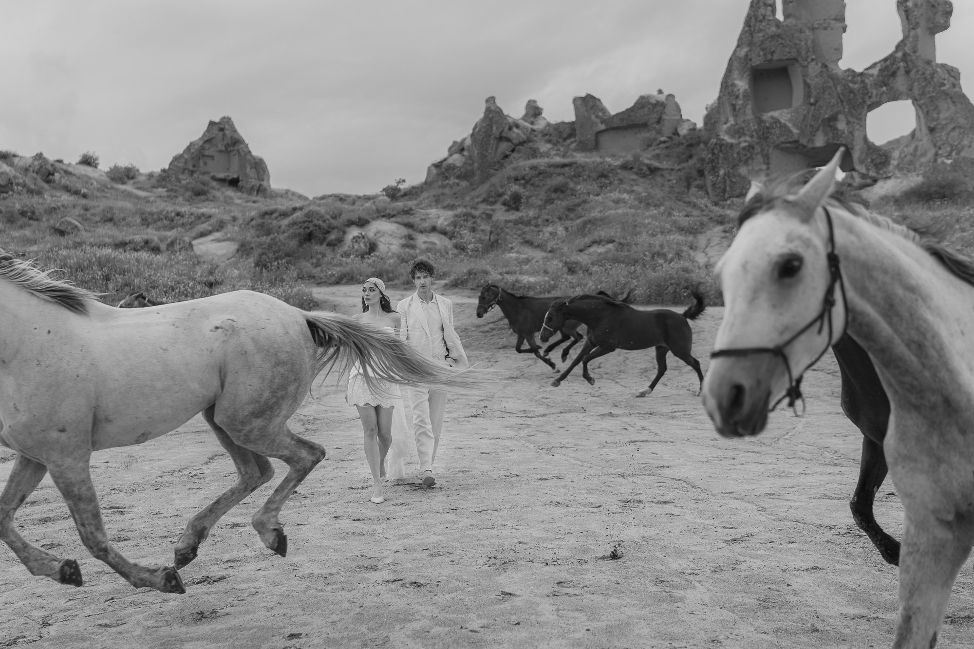 Black and white image of horses running through open Cappadocia landscape — documentary photography