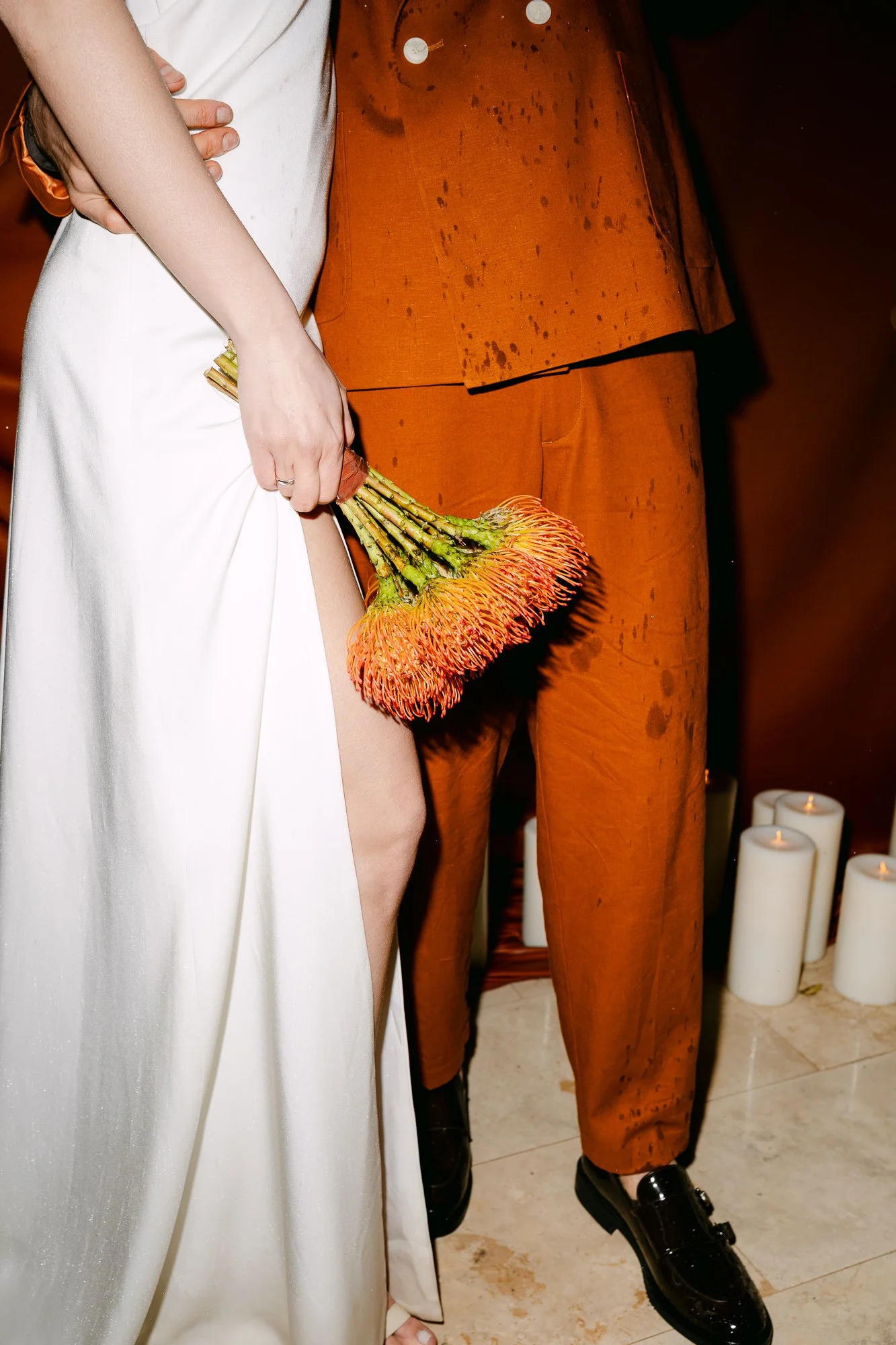 Detail of white wedding dress hem with yellow flower — editorial wedding photography