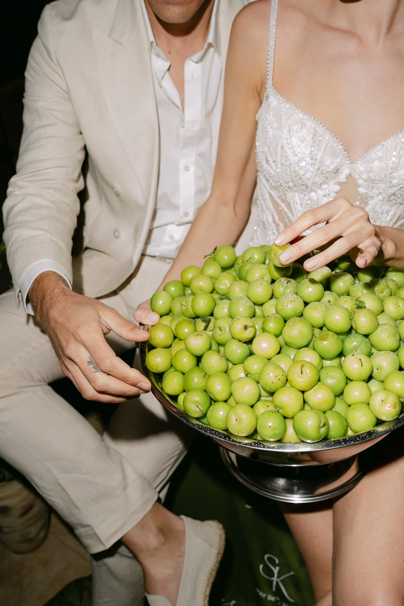 Groom holding bowl of green apples beside bride in white dress — Cappadocia wedding photography
