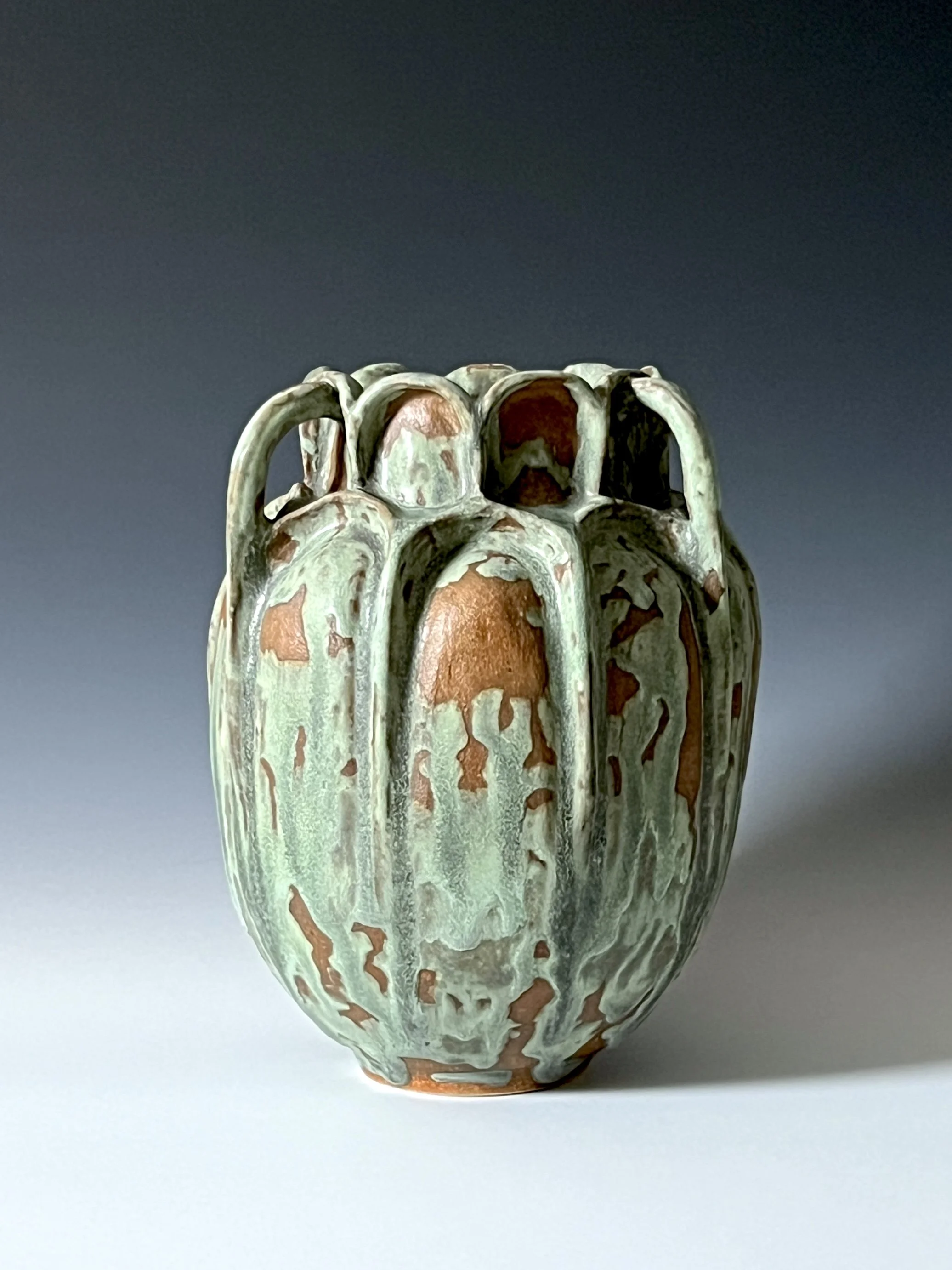 Ceramic vase with a textured, glazed surface featuring drip and crackle patterns in green, brown, and cream colors.
