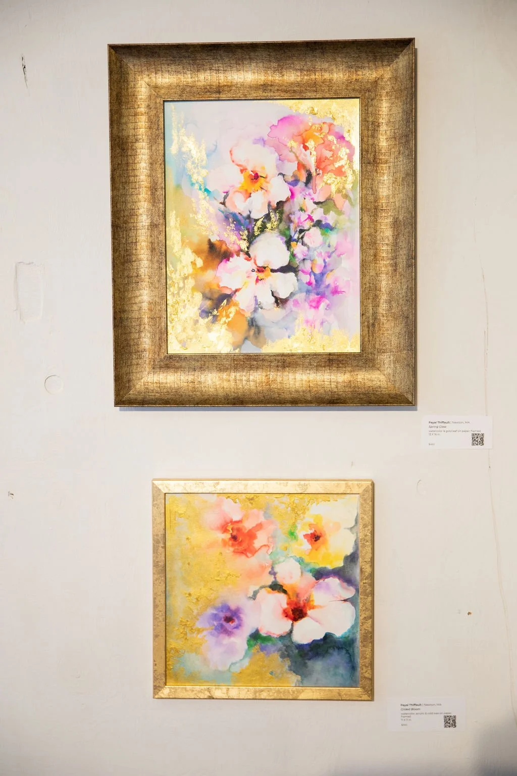 Two framed floral watercolor paintings with vibrant colors, mounted on a white wall.