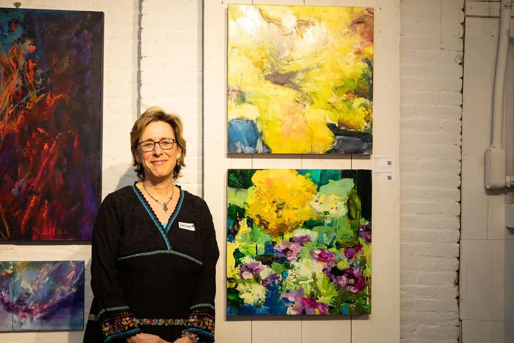 Woman standing next to abstract paintings on a gallery wall