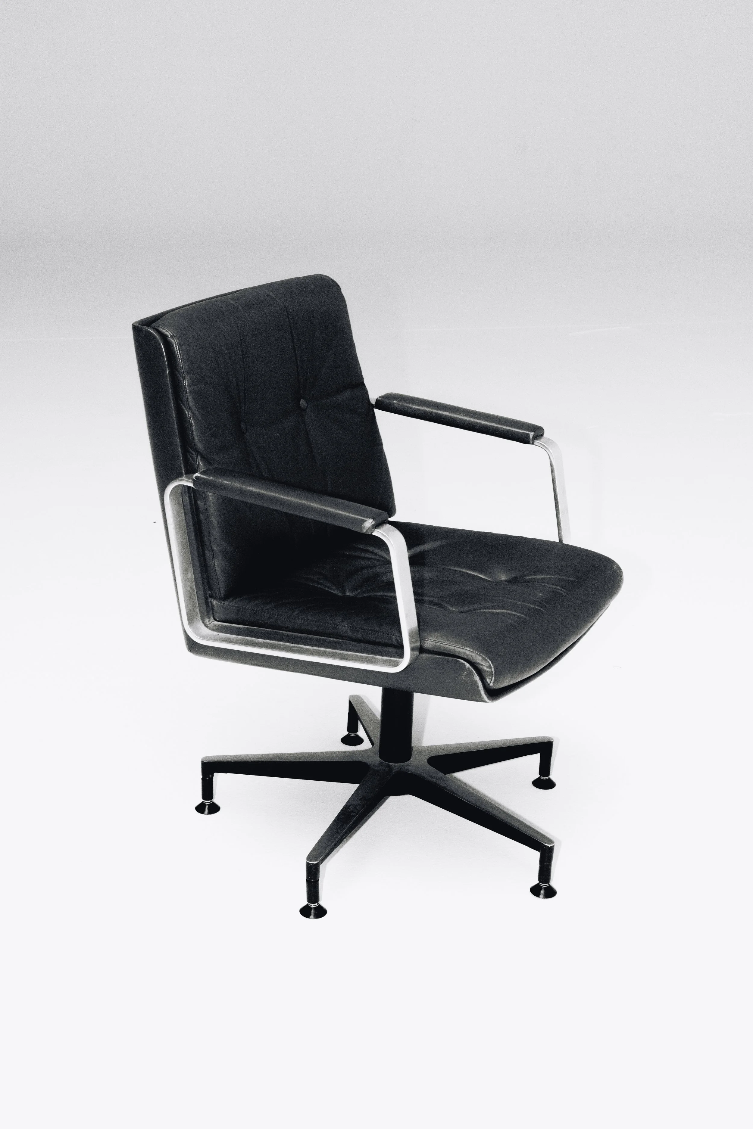 Black leather office chair with metal armrests and a swivel base, set against a plain white background.