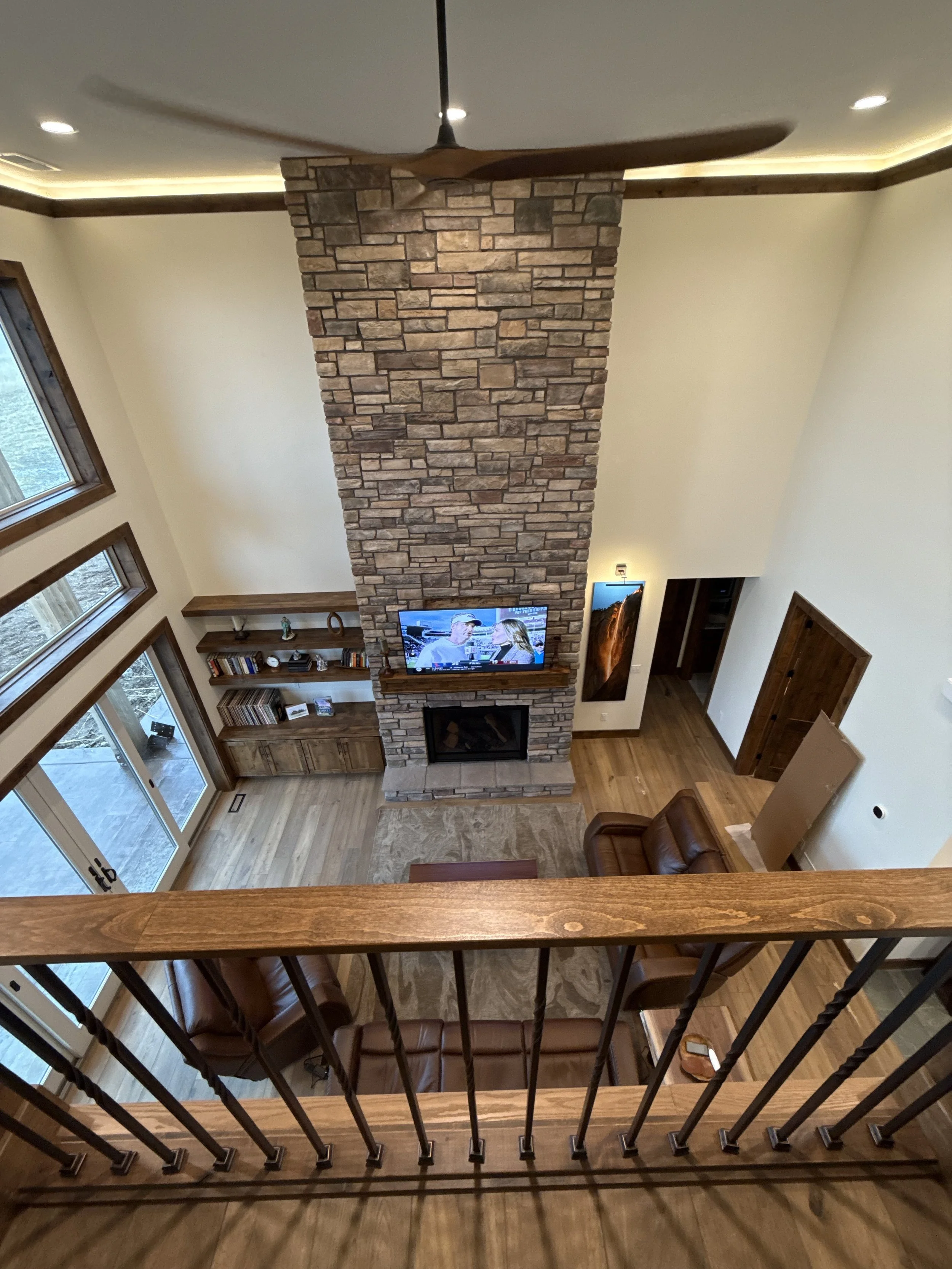 Two-story great room with floor-to-ceiling stone fireplace and large windows in an Eastern Idaho custom home.