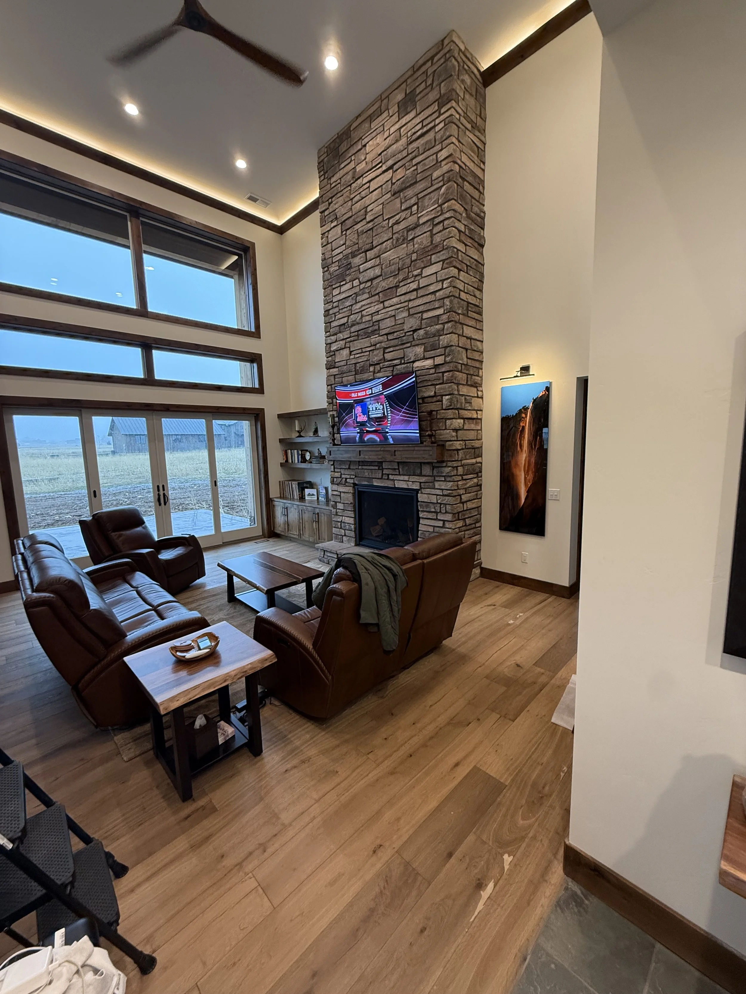 Luxury custom home living room with floor-to-ceiling stone fireplace and large windows built by Swager Builds in Eastern Idaho