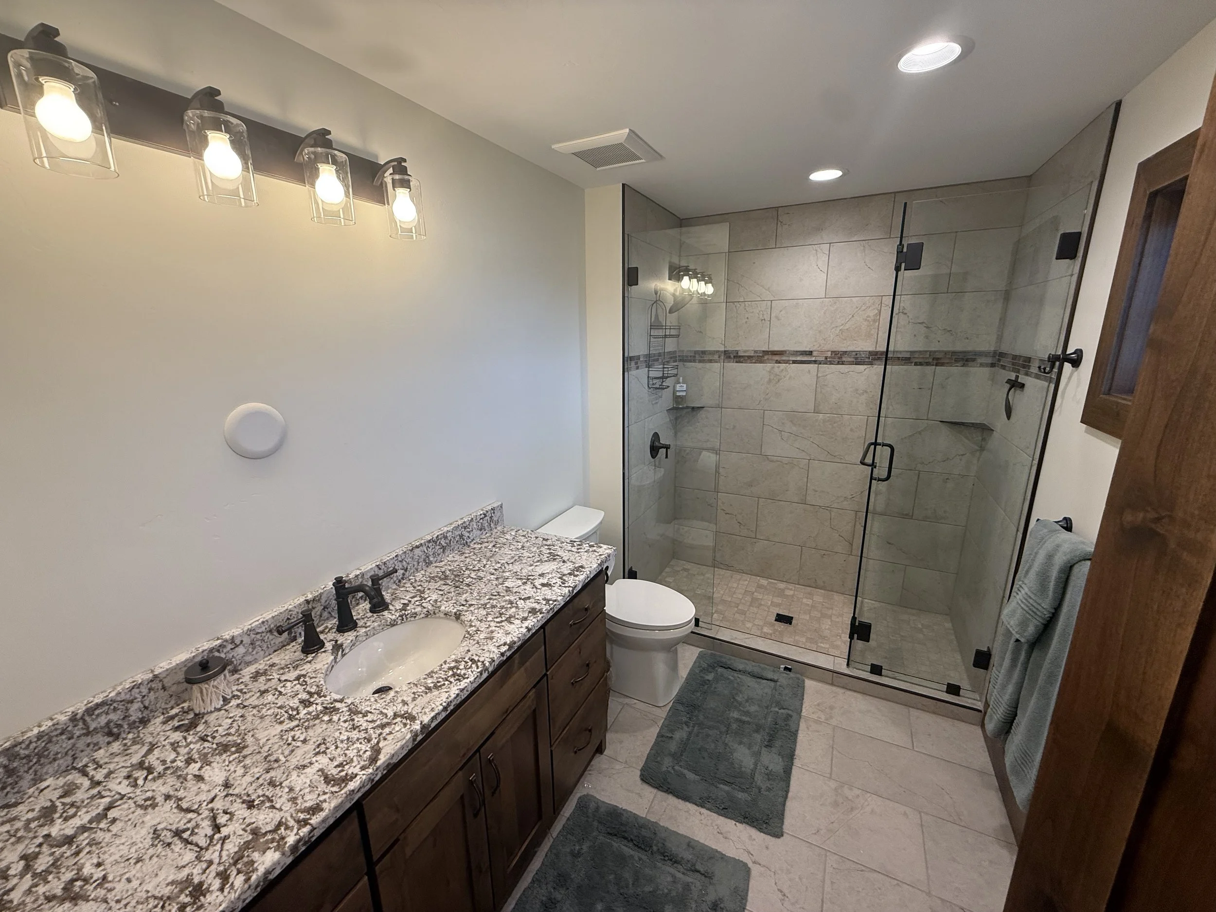 Master bathroom with granite double vanity, glass shower, and modern lighting in an Eastern Idaho custom home.