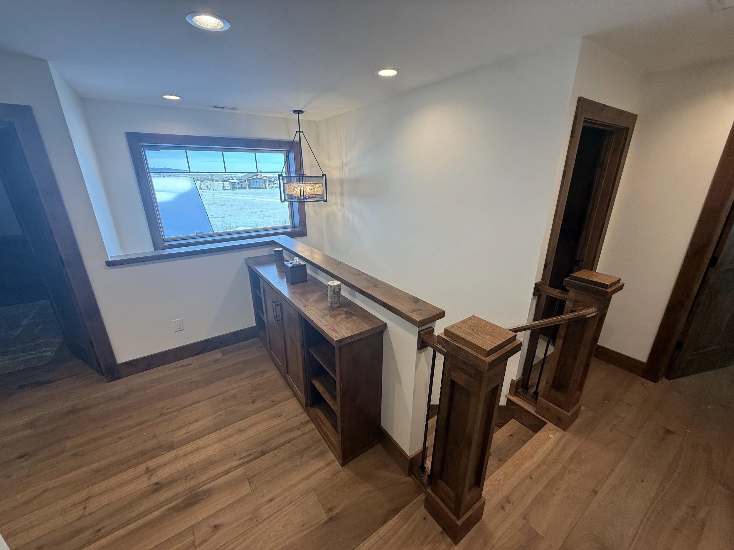 Custom home interior with wood railing, hardwood flooring, and modern lighting in a luxury Eastern Idaho home.