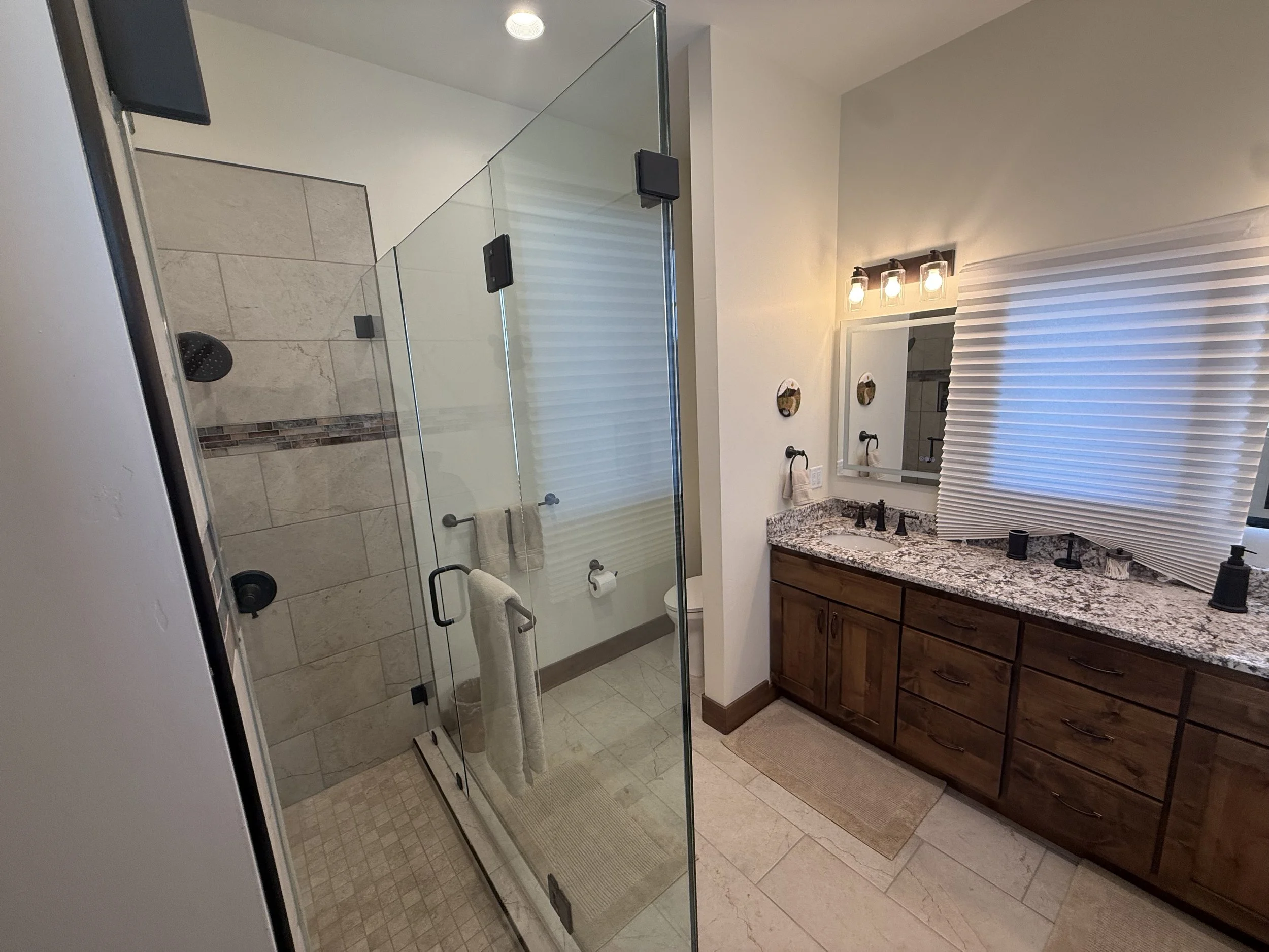 Custom bathroom with glass shower enclosure, granite vanity, and tile flooring in an Idaho Falls area custom home.