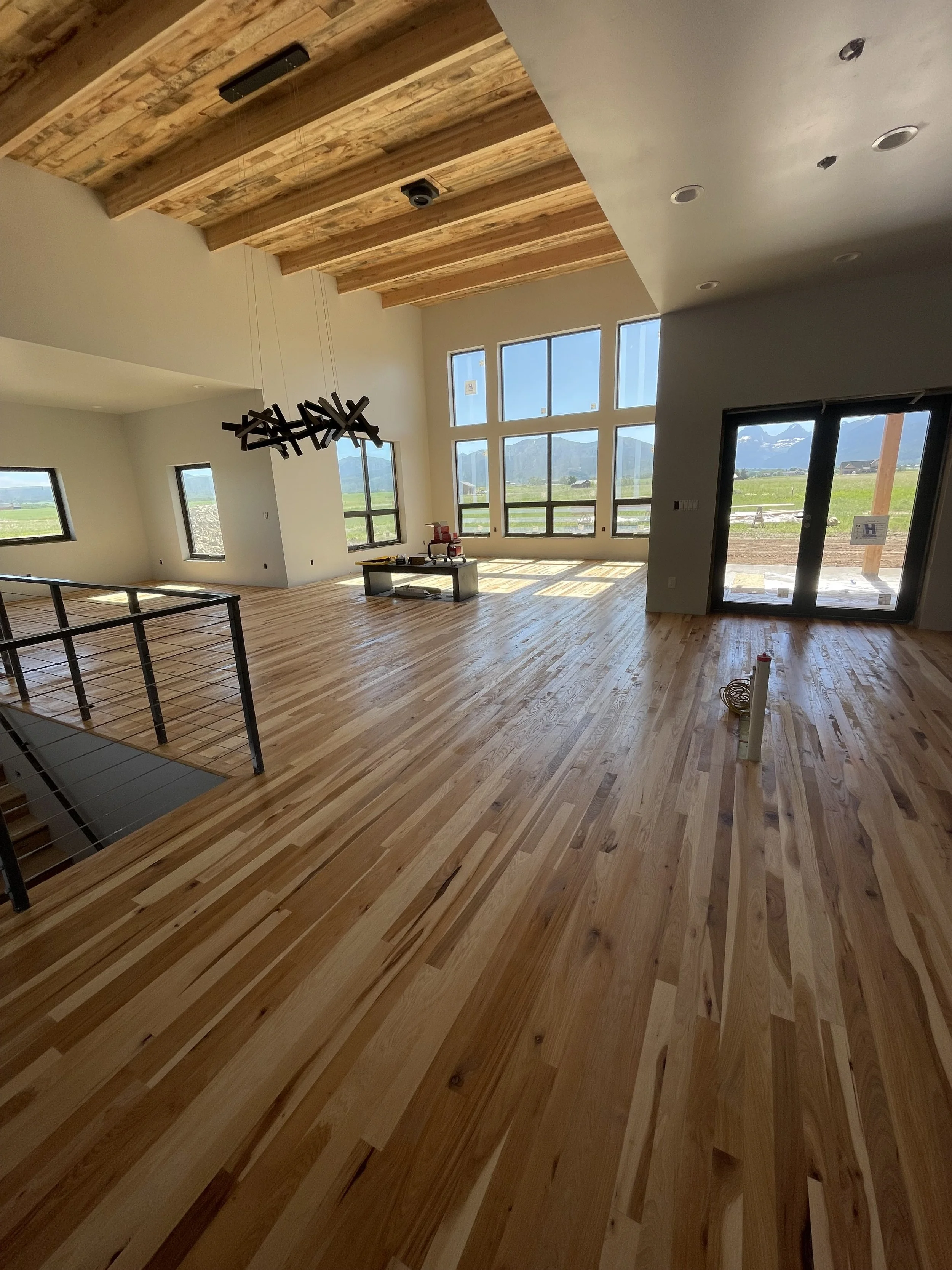 Luxury great room with hardwood floors, vaulted ceilings, and large window wall in an Eastern Idaho custom home.
