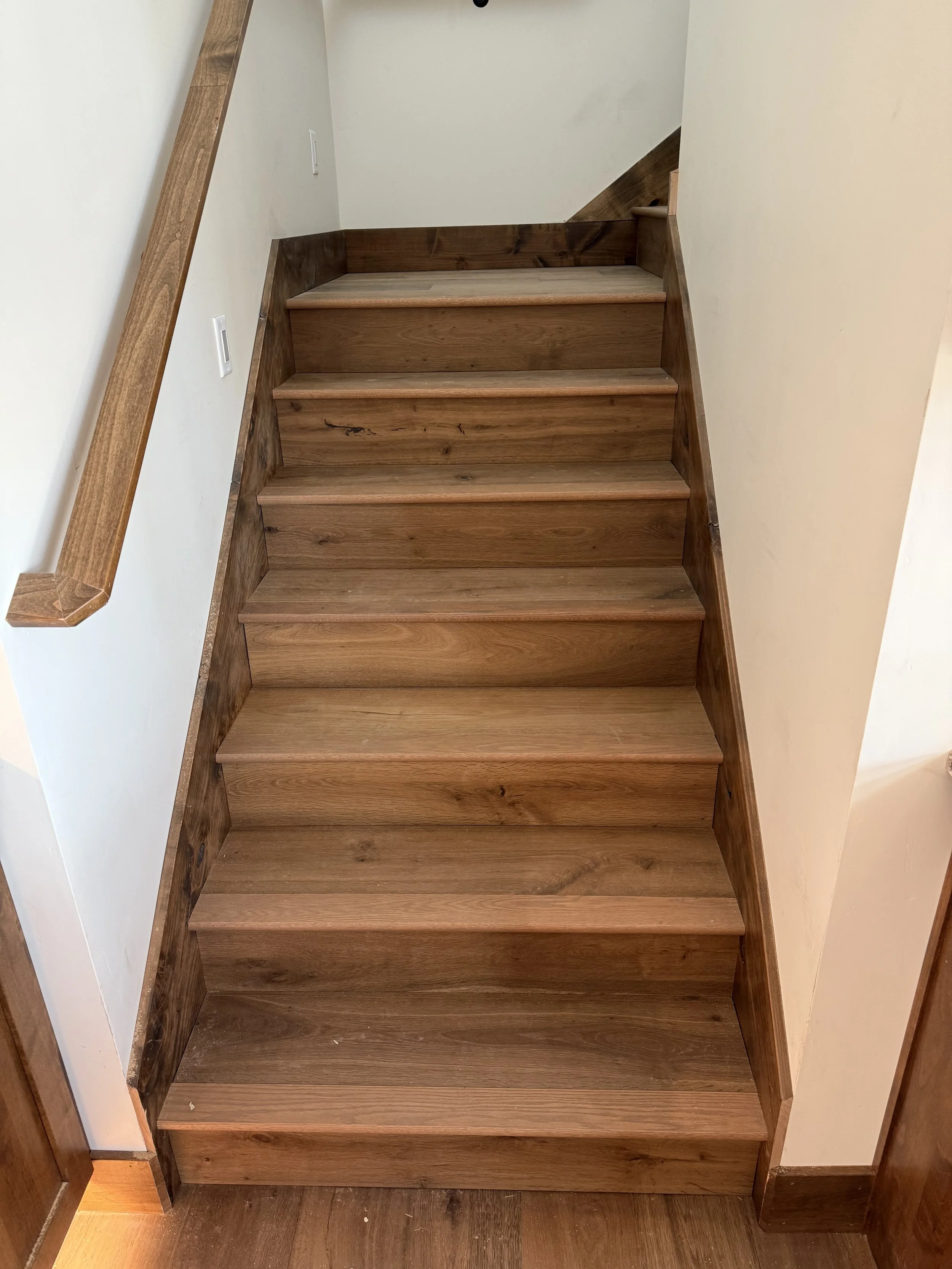 Wooden staircase with a handrail on the left side, leading upward.