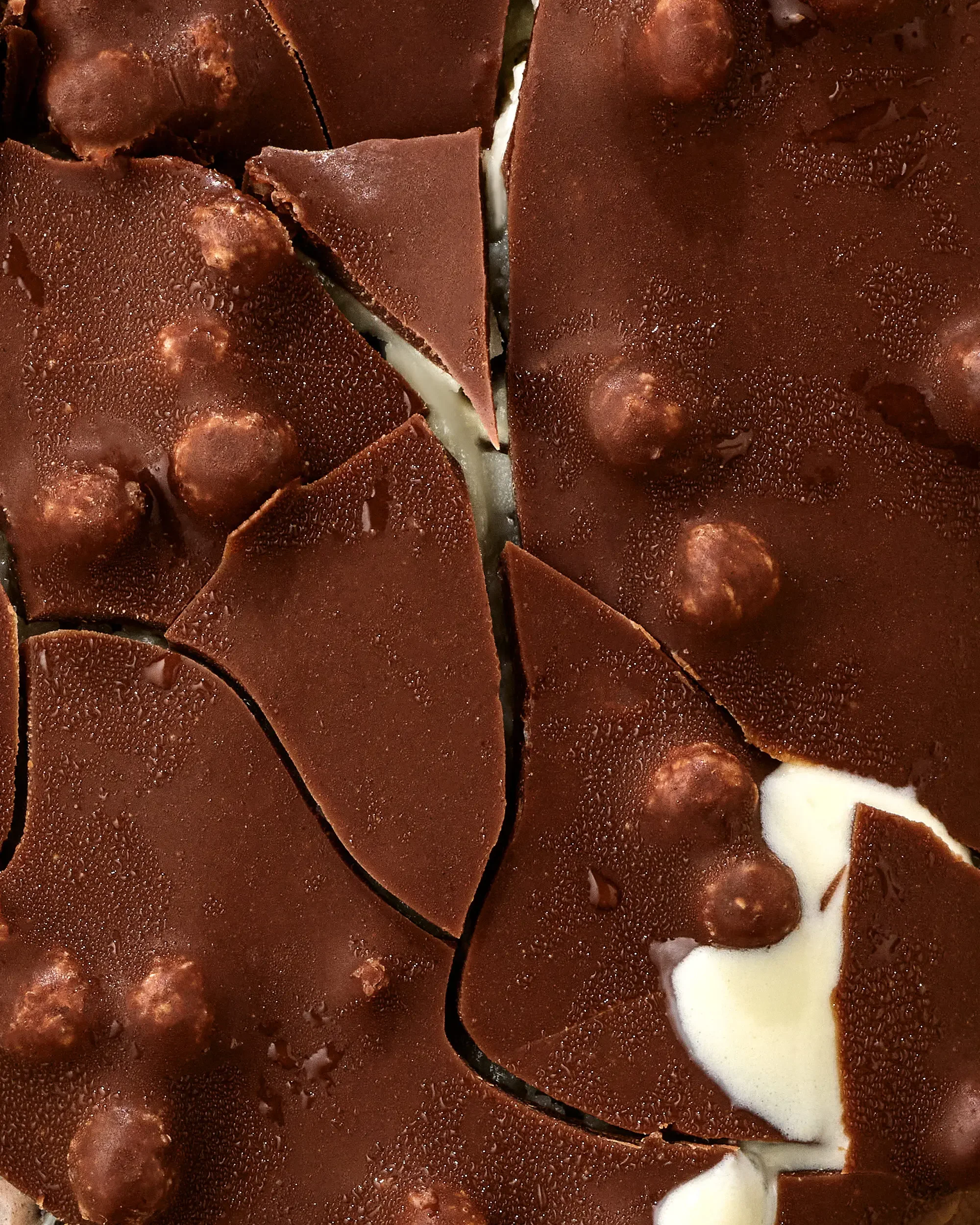 Close-up of a chocolate dessert with visible chocolate chips and a white filling, cut into slices.