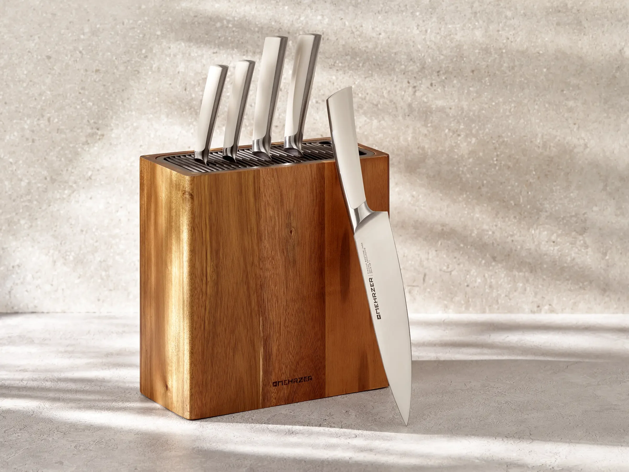 A wooden knife block holding several stainless steel knives with white handles and one knife leaning against it.