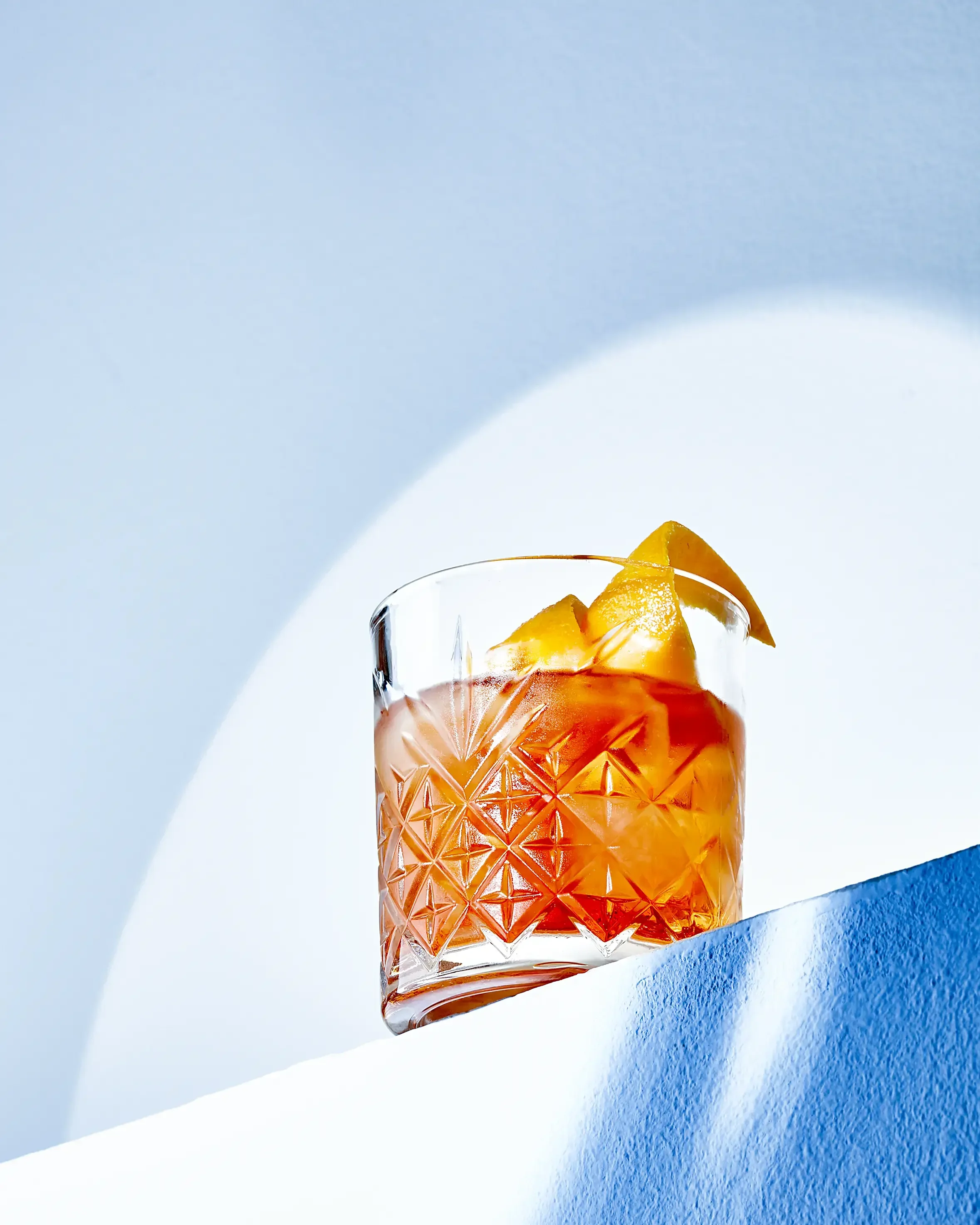 A glass of iced tea with lemon wedges on a white and blue background.