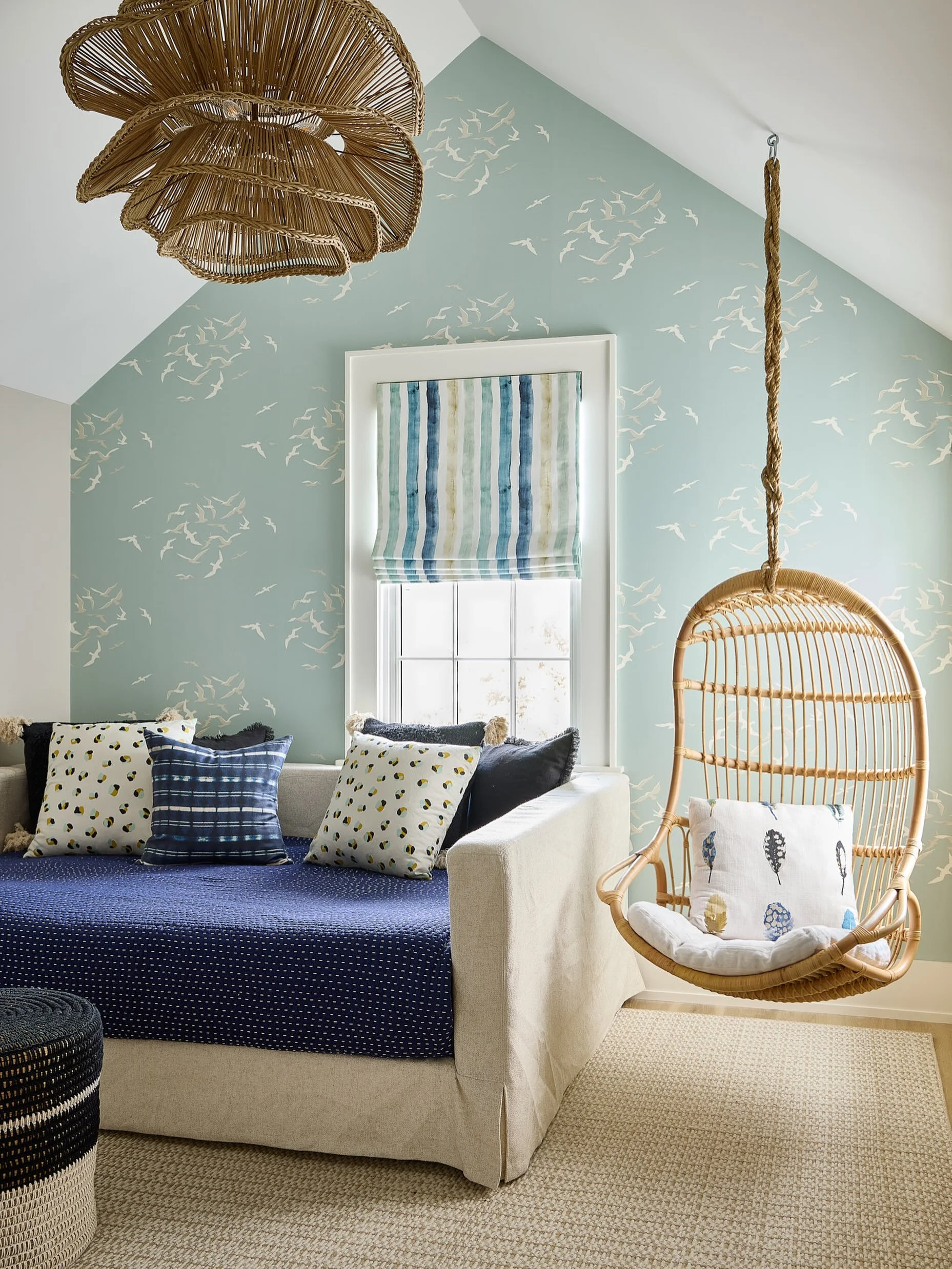 Some rooms are just built for daydreaming. This Nantucket bunk room mixes a woven shell pendant, a rattan hanging chair, and seagull wallpaper that somehow makes even a rainy day feel like the beach. Every pillow tells a different pattern story, dots