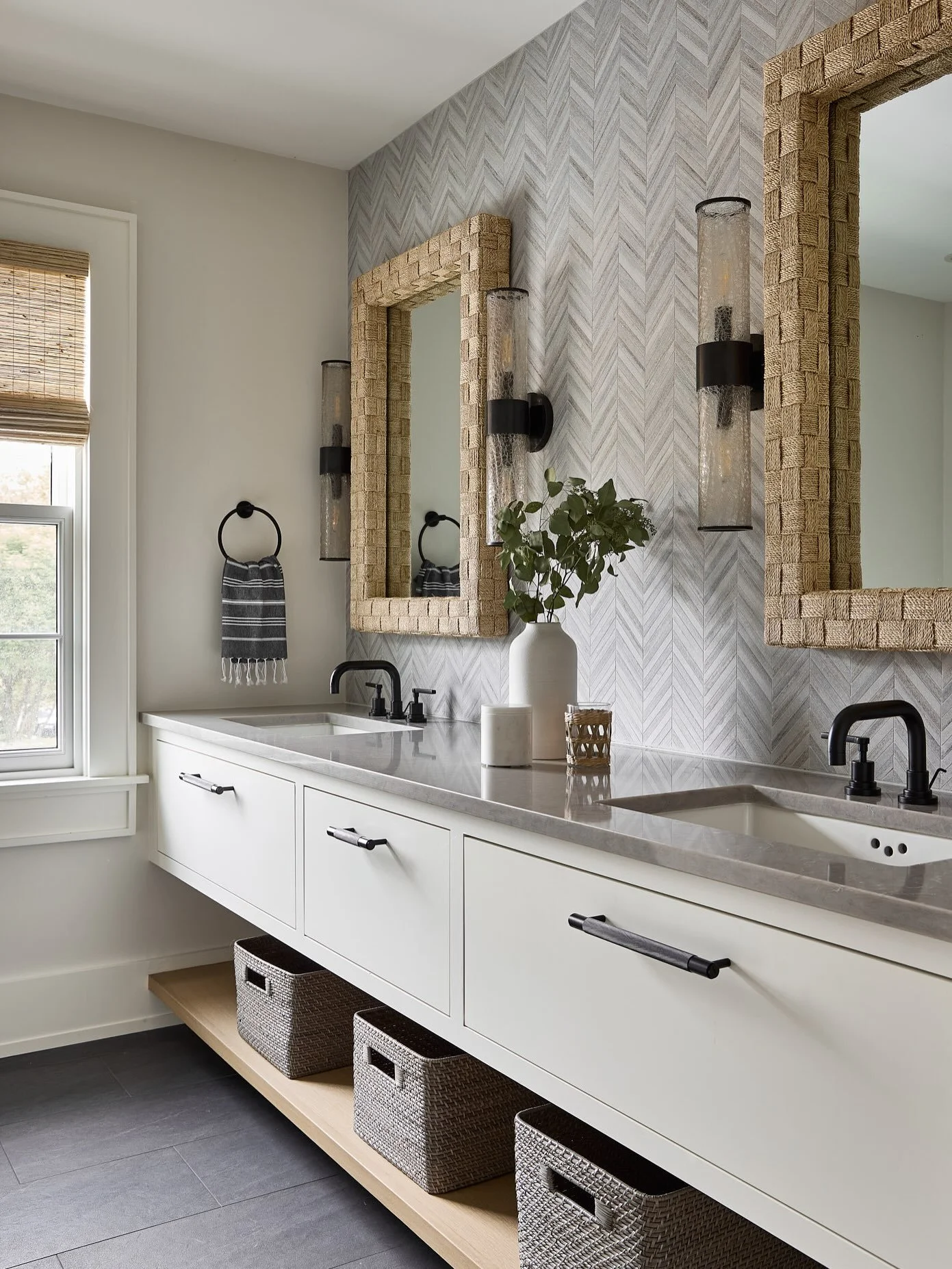 There&rsquo;s a formula I keep returning to: let gray and black carry the quiet, and give natural materials the only job of adding warmth.

In this Nantucket primary bath, herringbone stone sets a cool, disciplined backdrop. Black fixtures hold the l