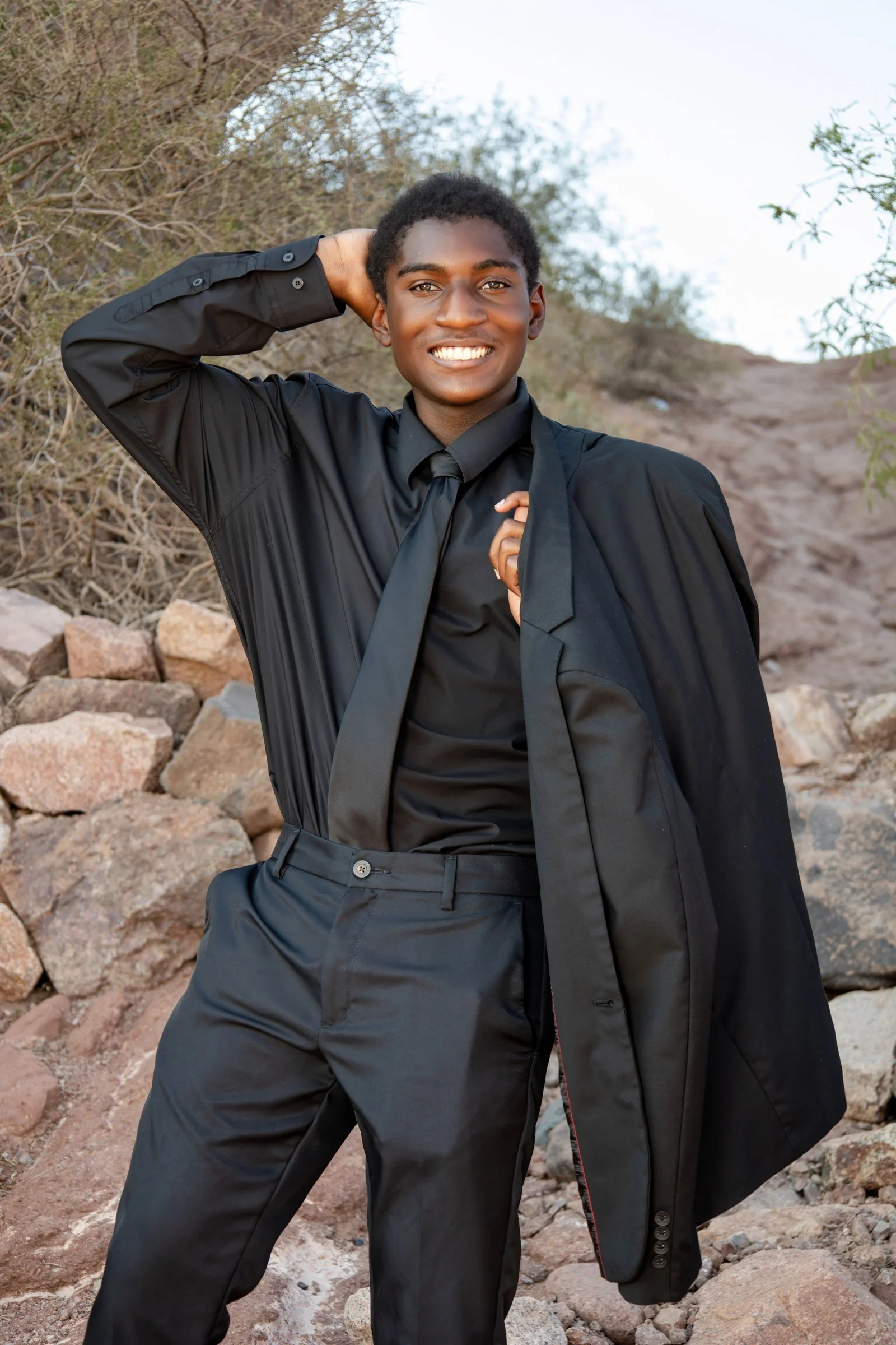 Phoenix senior pictures - Kai black suit against the red rock