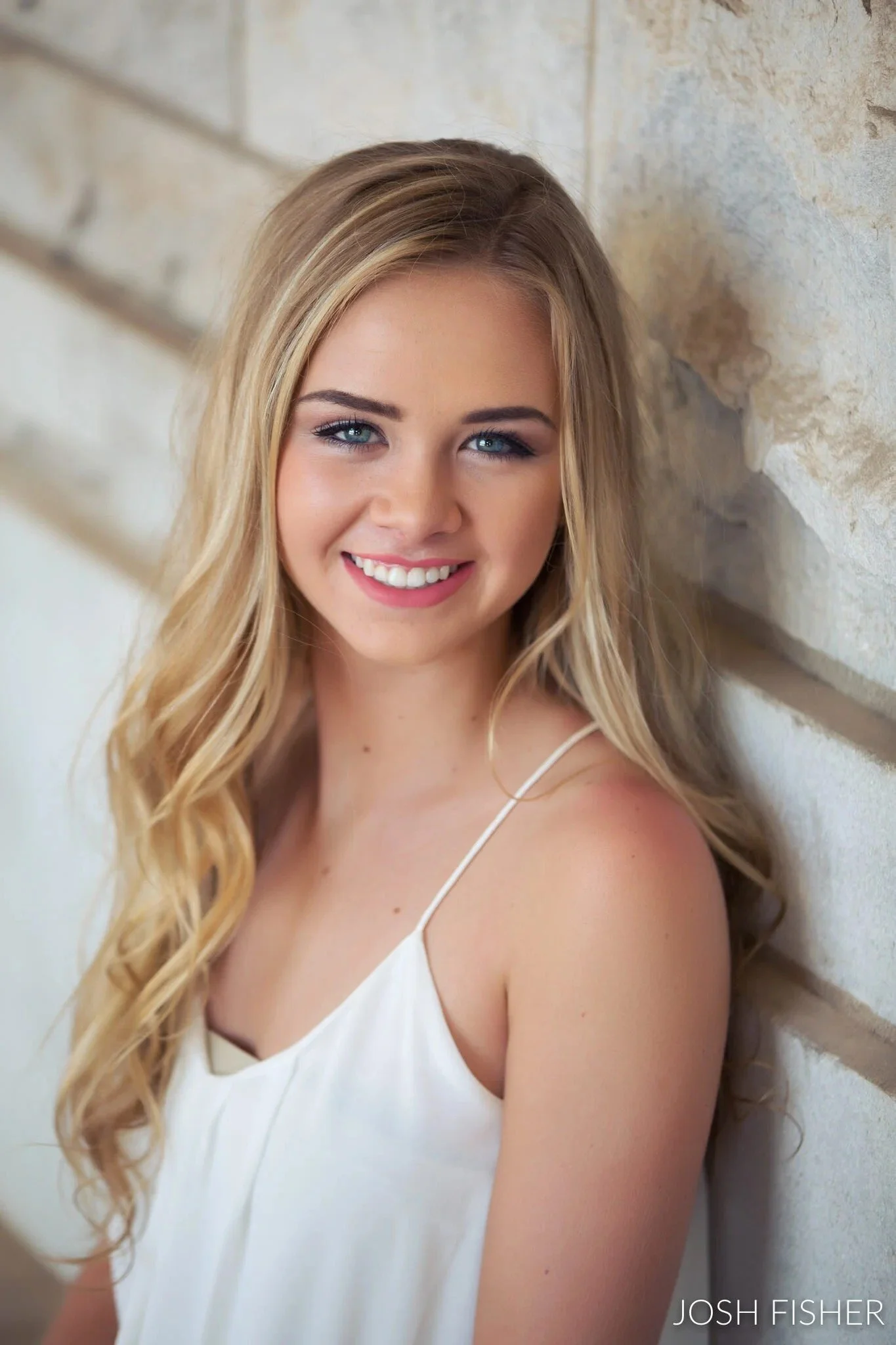 Dallas-Fort Worth senior portrait, girl with long blonde hair in a white spaghetti-strap top leaning against a wall