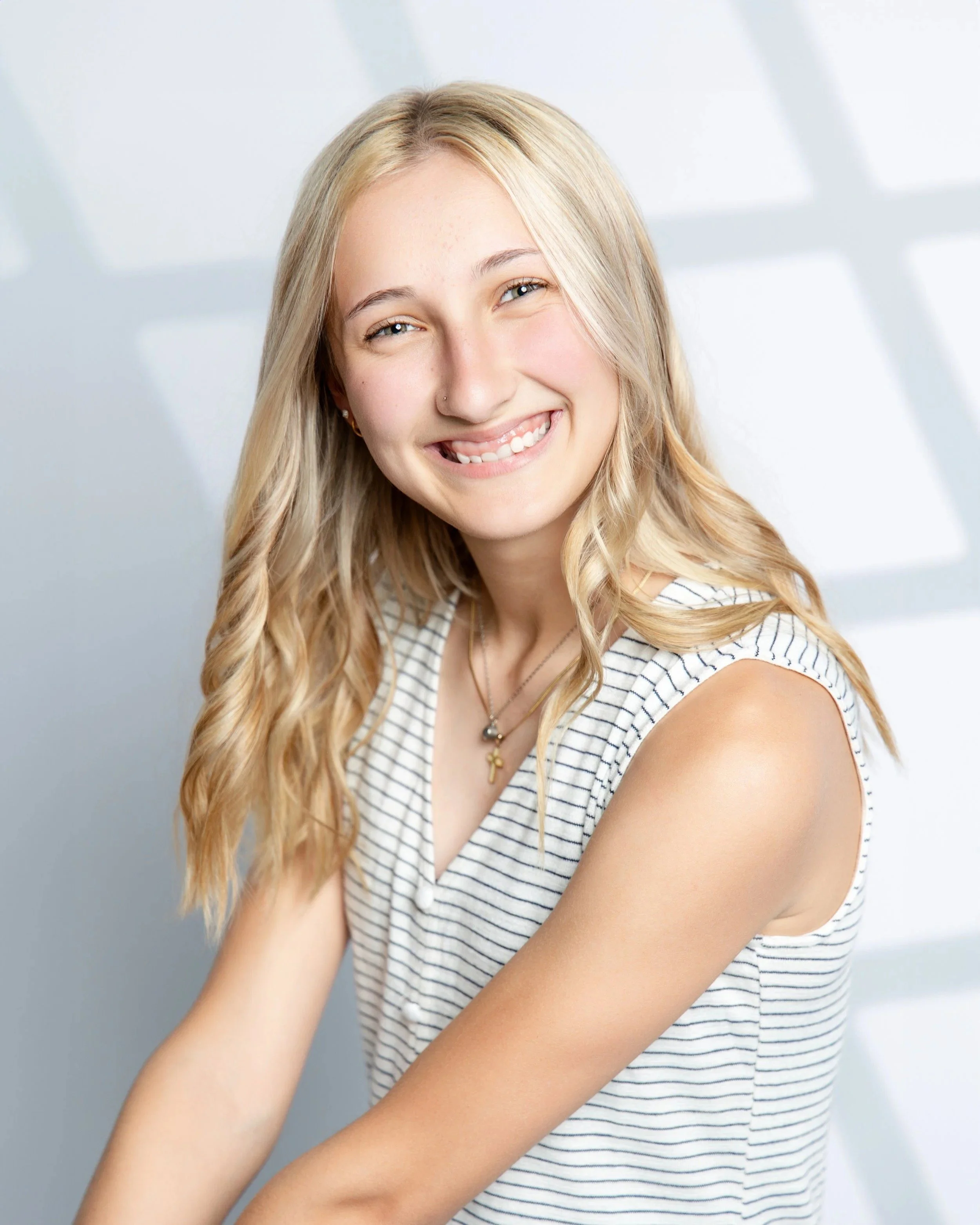 Senior portrait: smiling blonde girl in a striped sleeveless top and gold necklace