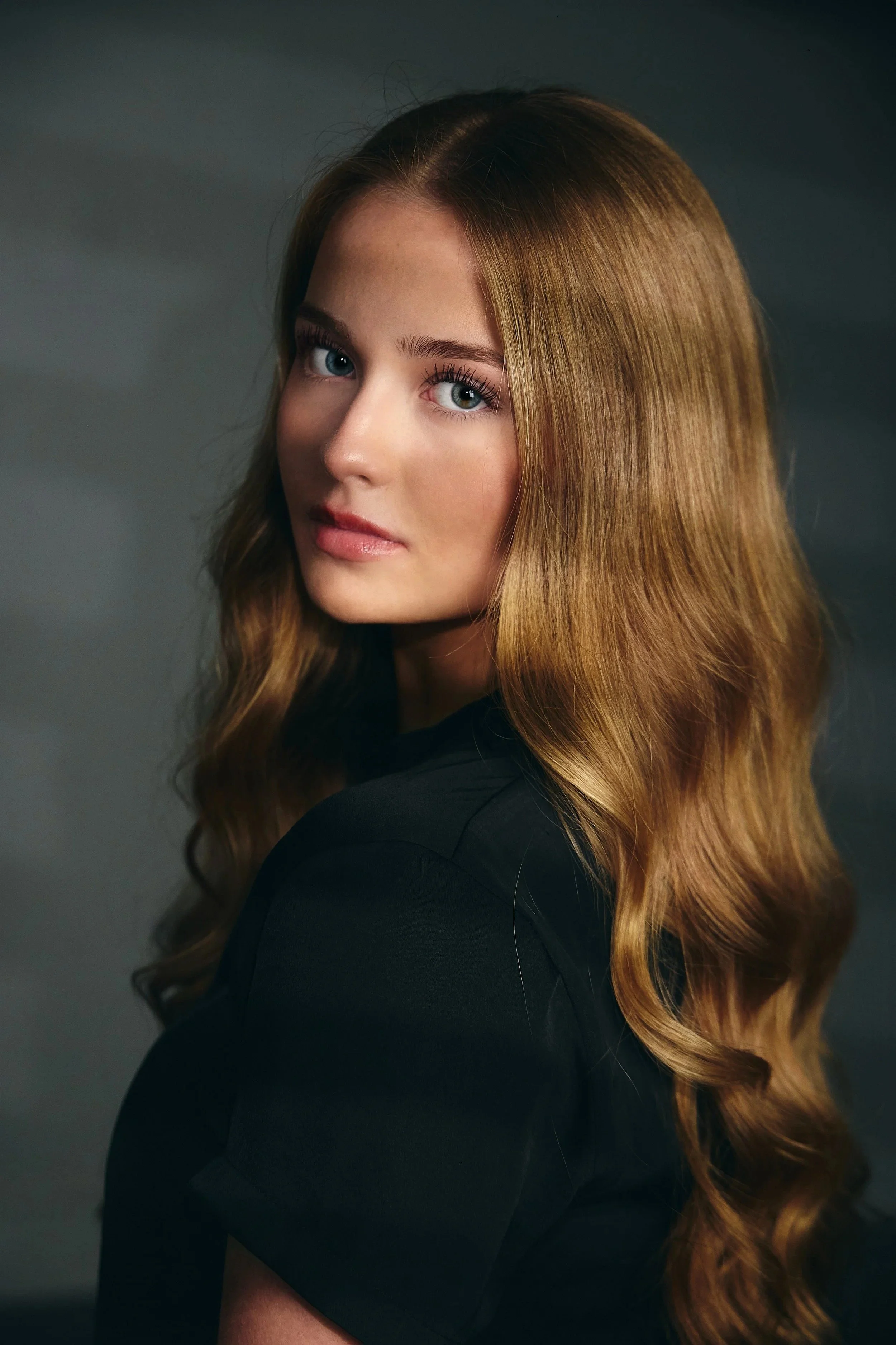 Senior picture wall art idea: girl with long wavy red hair in a black top against a dark background