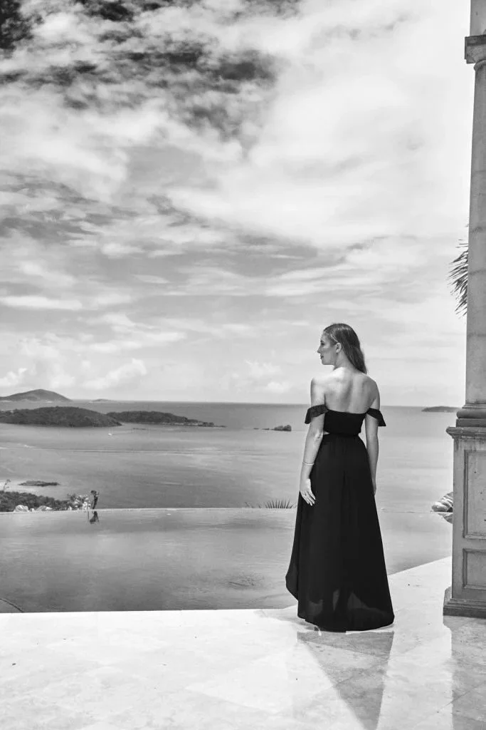 Senior picture outfit: girl in a long black off-the-shoulder dress outdoors overlooking the water