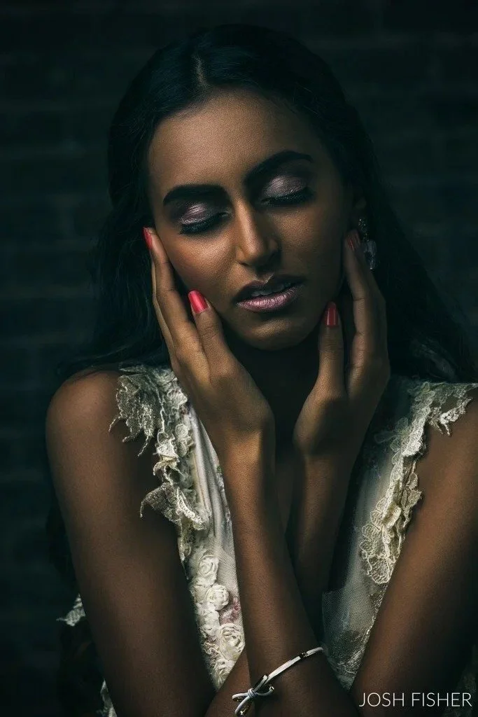 Senior picture outfit for girls: dark-haired girl in a lace dress resting her face in her hands
