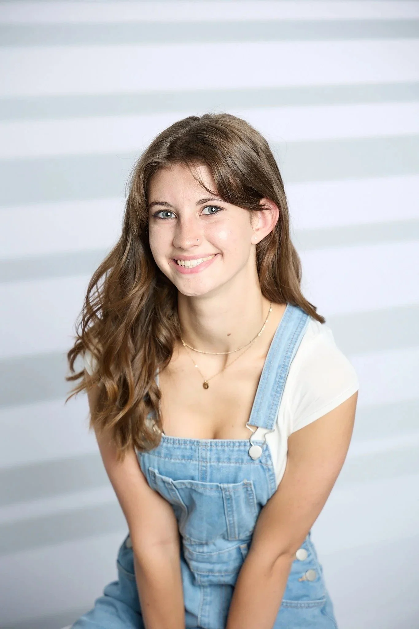 Senior picture pose: smiling girl with long wavy brown hair and blue eyes