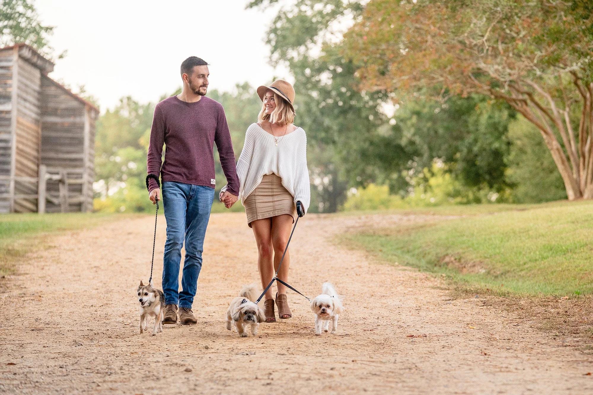 couple walking 3 small dogs down dirt path-1.jpg