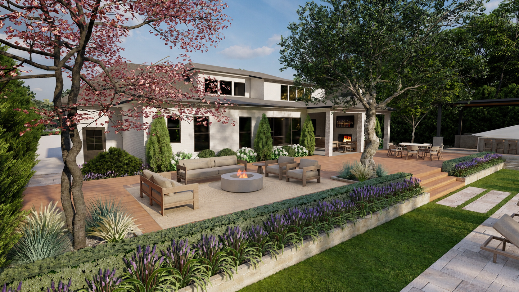 A spacious backyard patio with outdoor furniture, a fire pit, lush green lawn, flowering plants, trees, and a white house with large windows in the background.