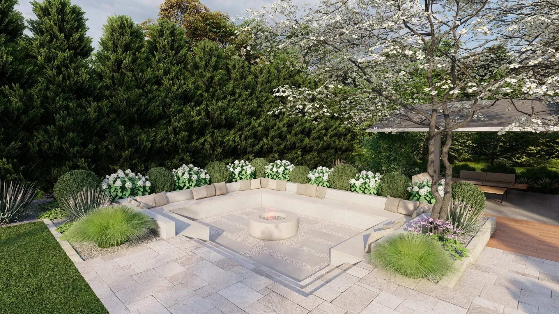 A modern backyard patio with a circular fire pit, surrounded by white concrete seating with beige cushions, lush green plants, and trees with white blossoms. There is a seating area with a canopy in the background, all set on tiled flooring.
