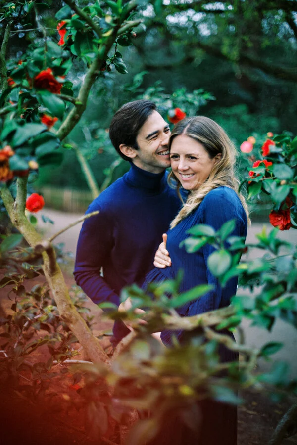 A close-up of a couple tightly hugging whilst pregnant during an outdoor family session in Holland Park.