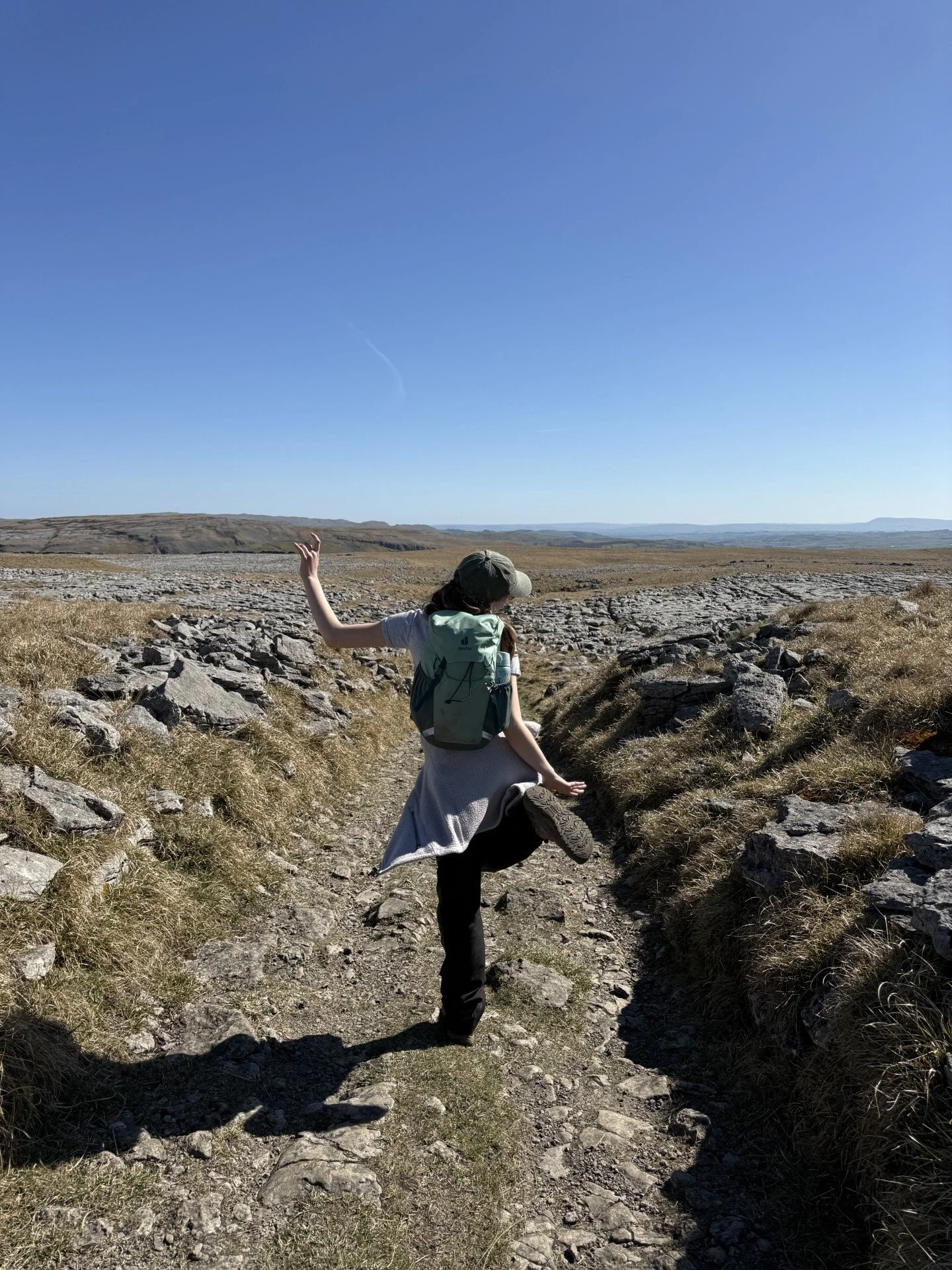 Child in dancing pose walking between two areas of limestone pavement