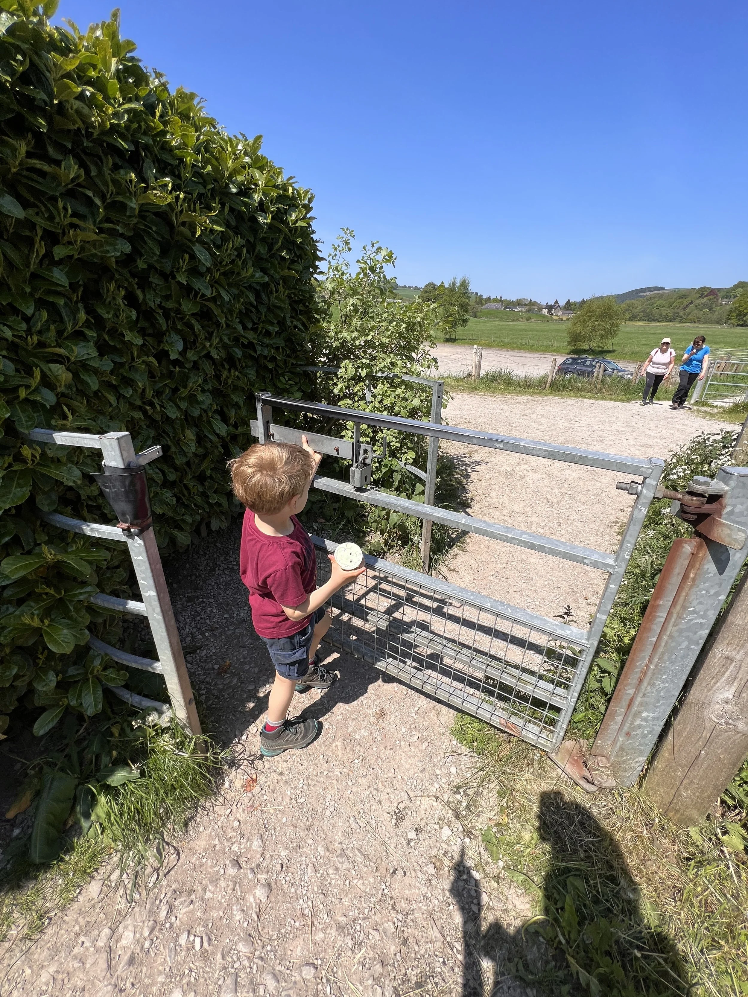Child walking through a metal kissing gate with ice cream